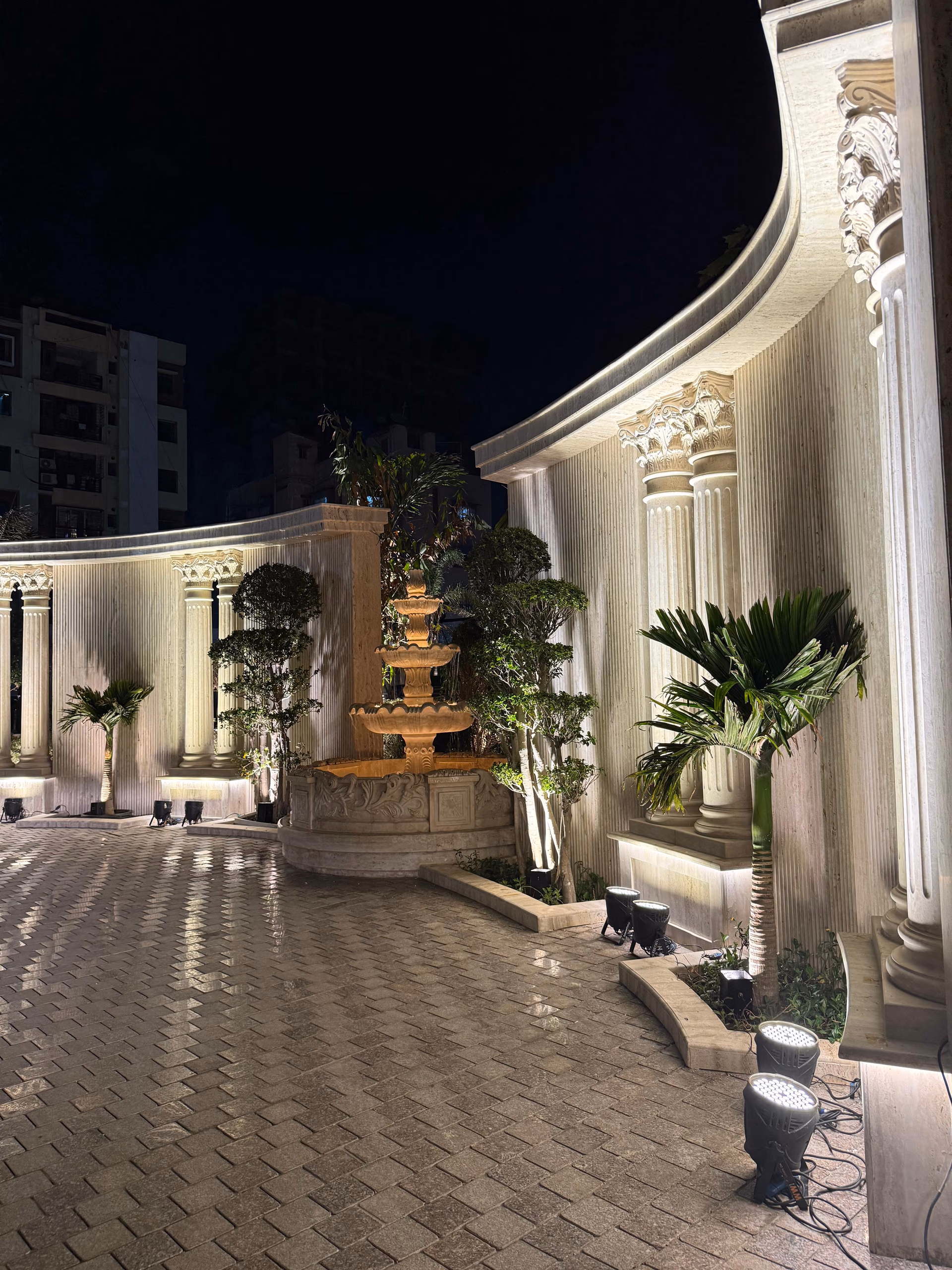 A Designatore-designed colonnaded courtyard with a tiered fountain, lit at night.