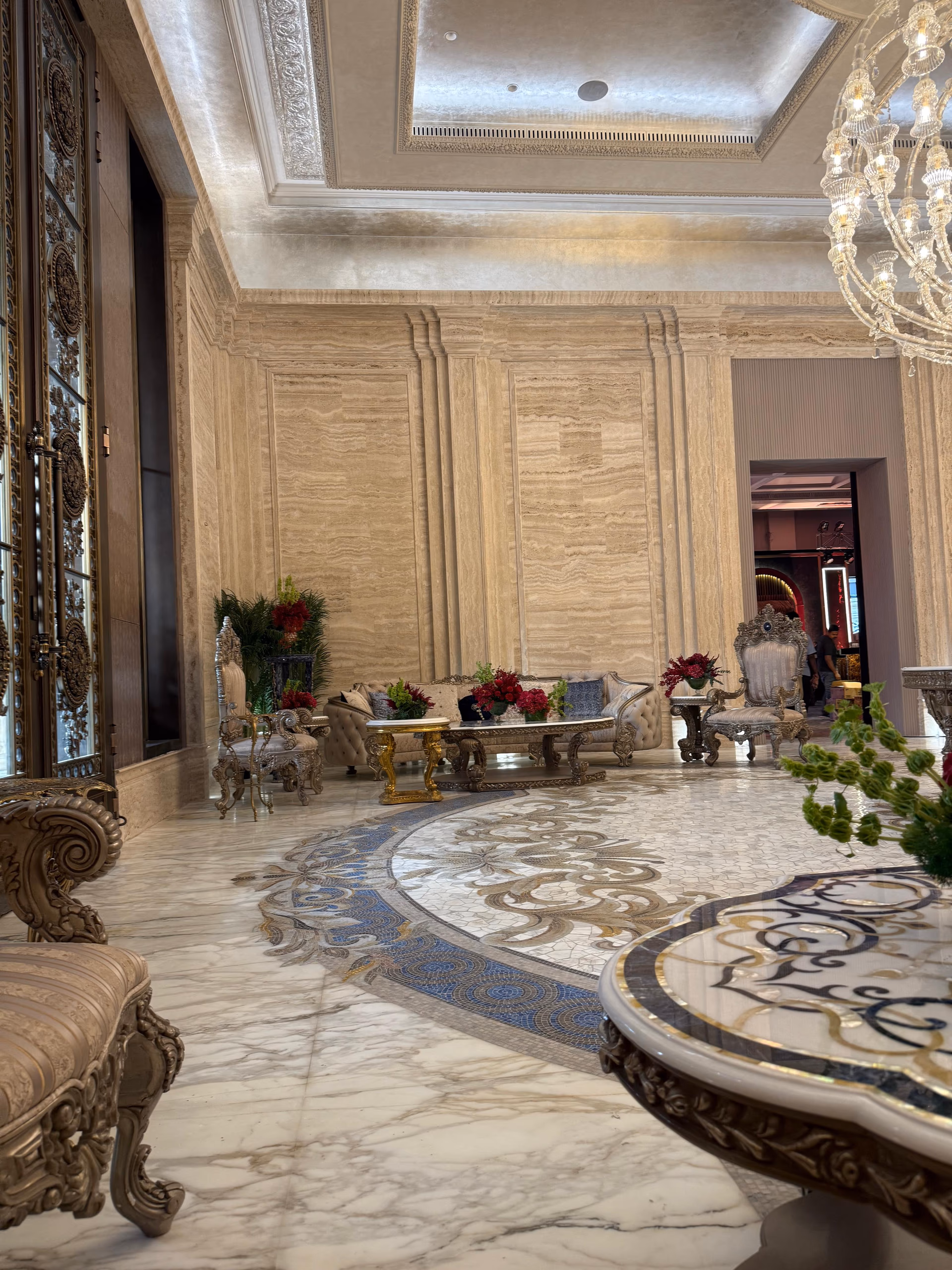 Formal living room with carved gilt-frame sofas and chairs, two gold coffee tables, a crystal chandelier, and an inlaid marble medallion floor.