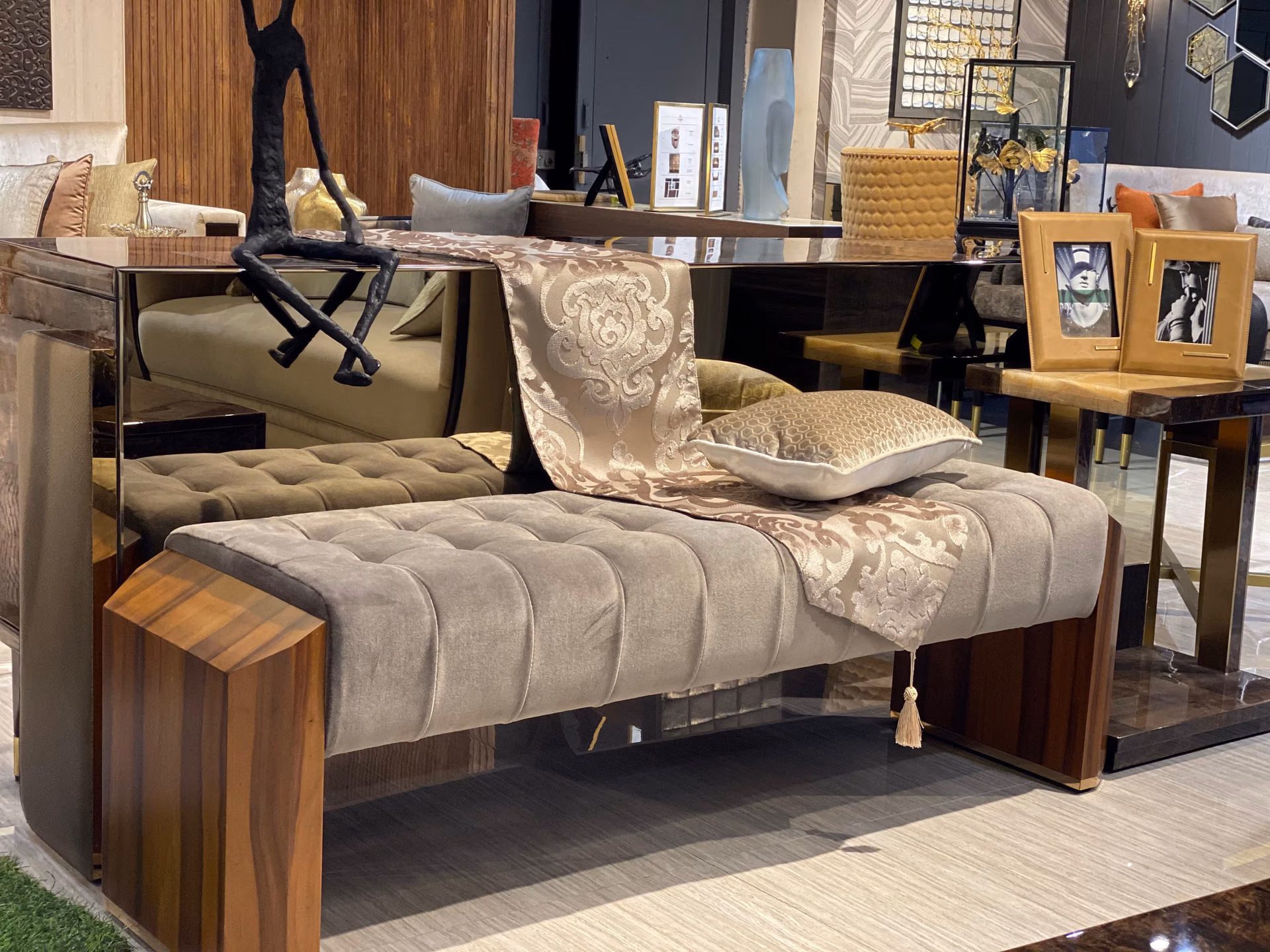 Backless bench with a grey channel-tufted velvet seat set between two chunky glossy walnut block arms, dressed with a woven runner and cushion.
