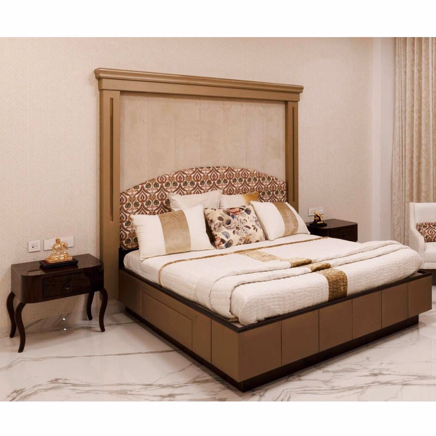 Floor-to-ceiling gold-framed headboard panel with a cream suede top section and an ikat-print upholstered bedhead, above a champagne storage bed with drawer fronts and cabriole-leg bedside tables.
