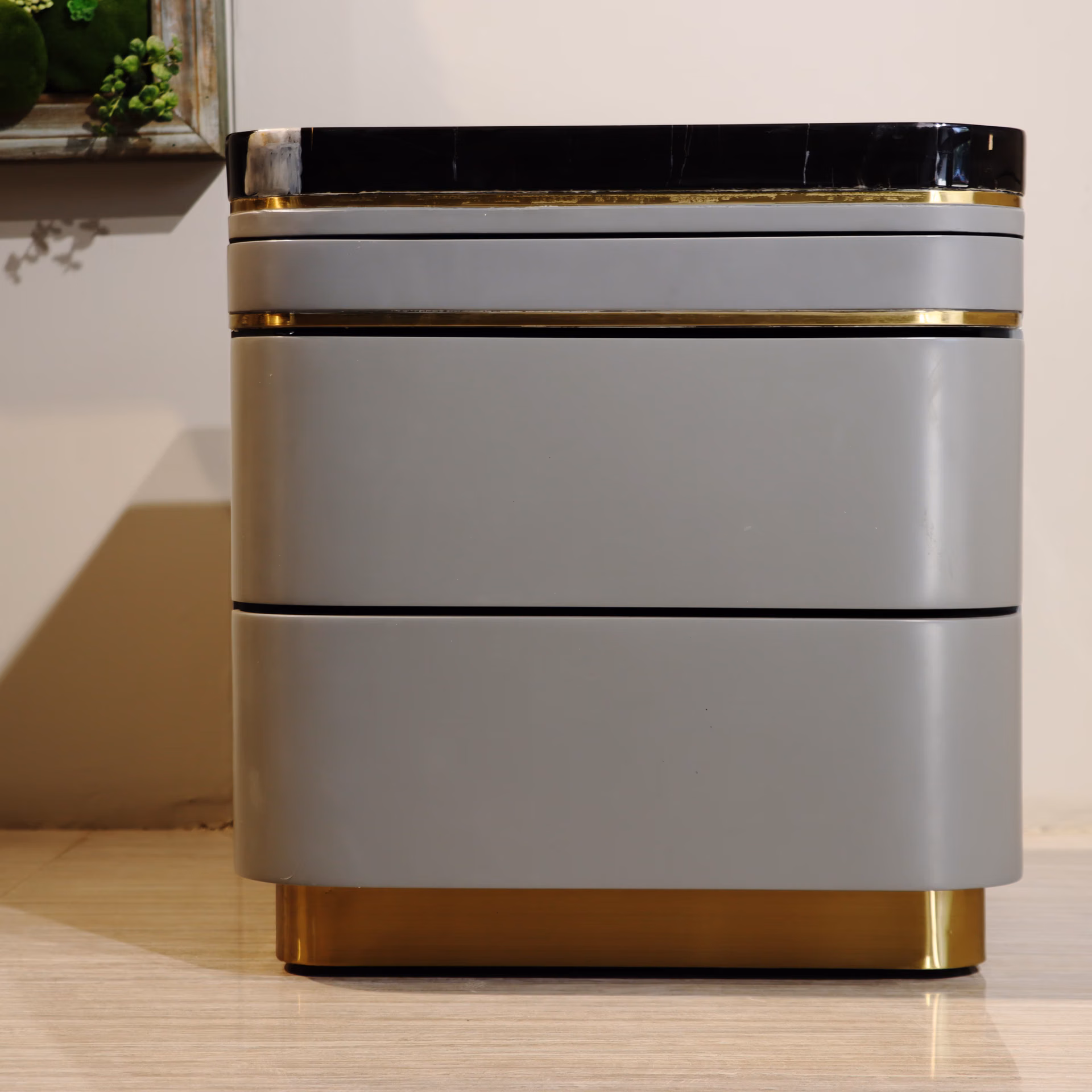 Grey high-gloss lacquer bedside table with black marble top and gold trim rings, two drawers, gold plinth base.