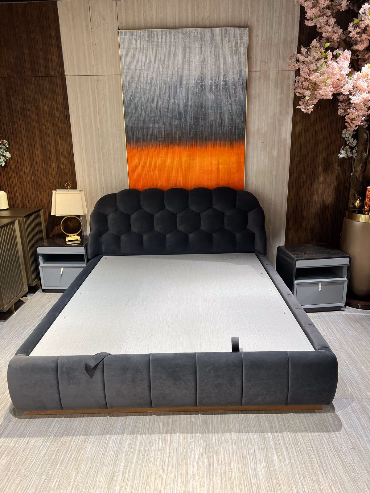 Black honeycomb-tufted velvet bed with a grey channel-tufted base, flanked by grey nightstands in a styled bedroom.
