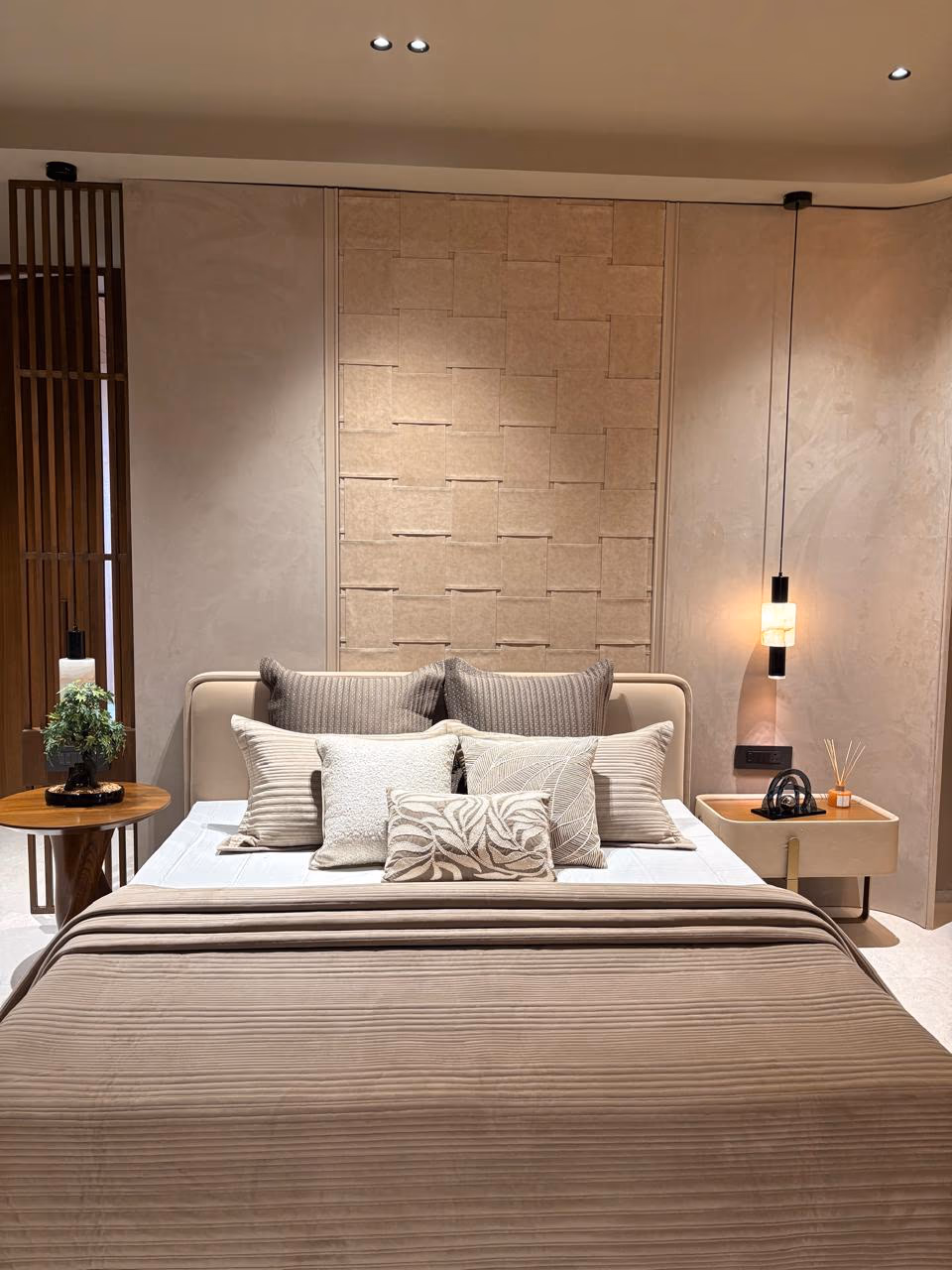 Black leather bed with a curved wingback headboard under a crystal drop chandelier, in a fluted walnut bedroom — the Designatore bedroom hero piece.