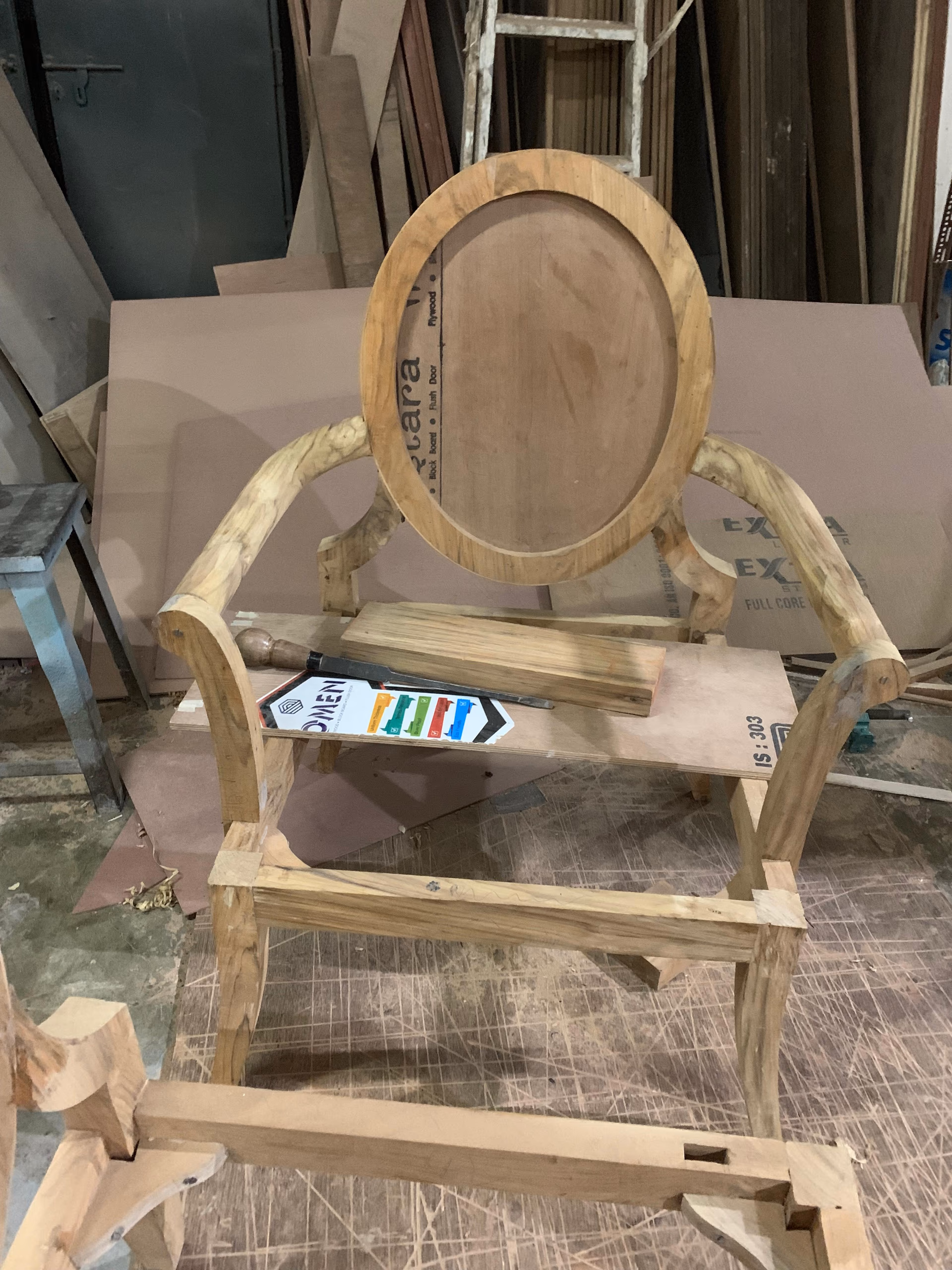 A teak chair frame with a carved medallion being built by hand from an approved furniture fabrication drawing.