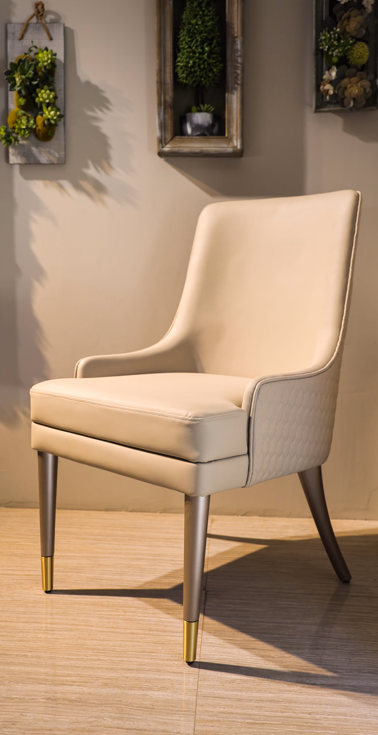 Cream leather dining armchair with curved arms, quilted side panel and brass-capped tapered legs.
