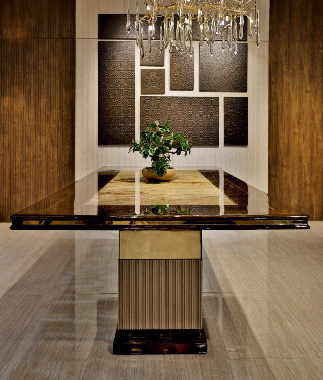 Rectangular dining table with a glossy burl-wood frame around an inset honey onyx top, raised on a fluted champagne pedestal with a dark plinth.