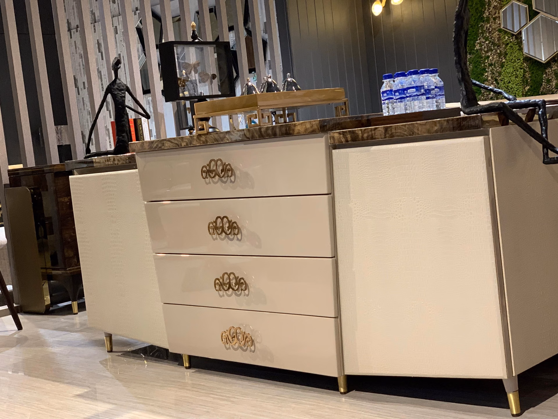 Three-quarter view of the cream croc-textured sideboard showing its depth, gloss drawers and marble top under warm showroom light.