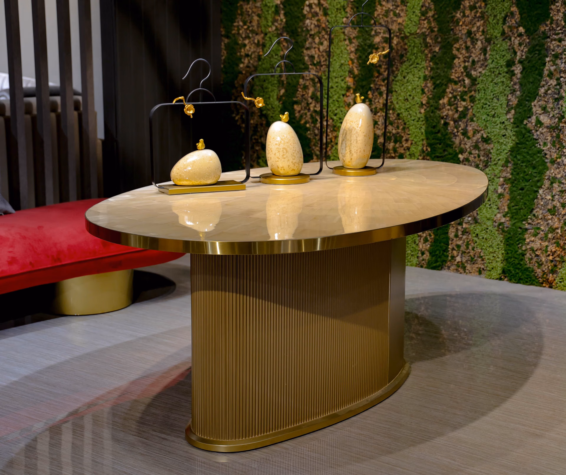 Oval dining table with a warm parquet stone top and a fluted brass drum pedestal base.