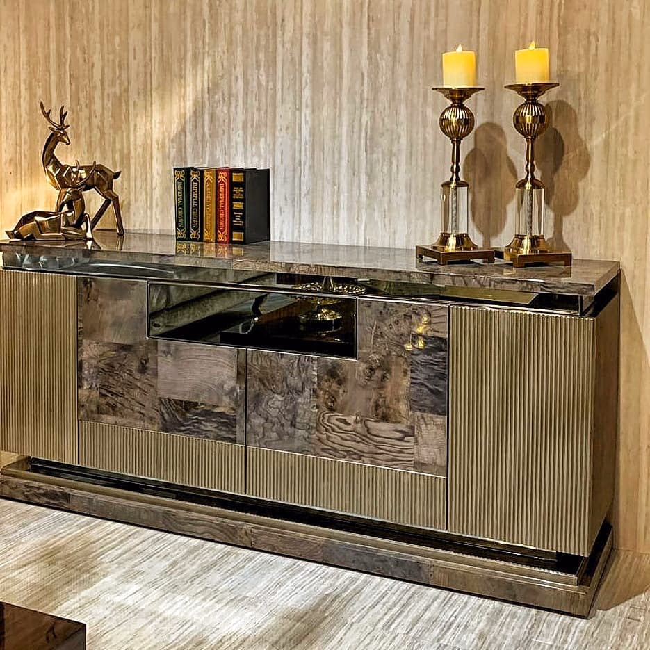 Dining sideboard with fluted champagne end doors, burl-wood and smoked mirror centre panels, a brown marble top and an open shelf, standing on a mirrored plinth.