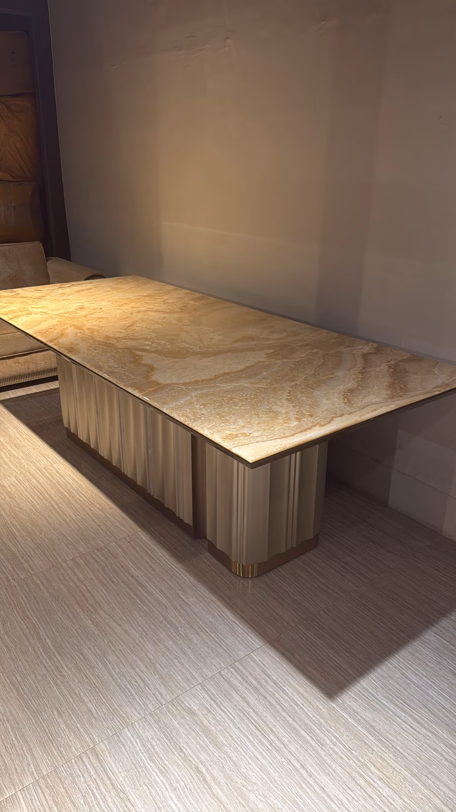 Rectangular dining table with a honey-gold marble top and two fluted champagne pedestal legs trimmed in brass.