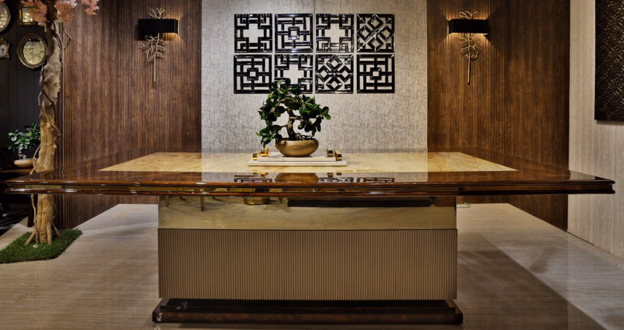 Straight-on view of the same onyx-top dining table showing its symmetric fluted base and mirror-like polished wood edge, styled with a small bonsai.