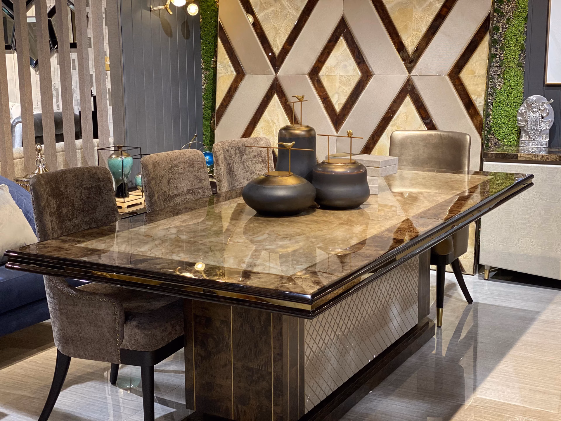Side view of the onyx dining table and its grey nailhead chairs, with a mirror-front sideboard to the right.