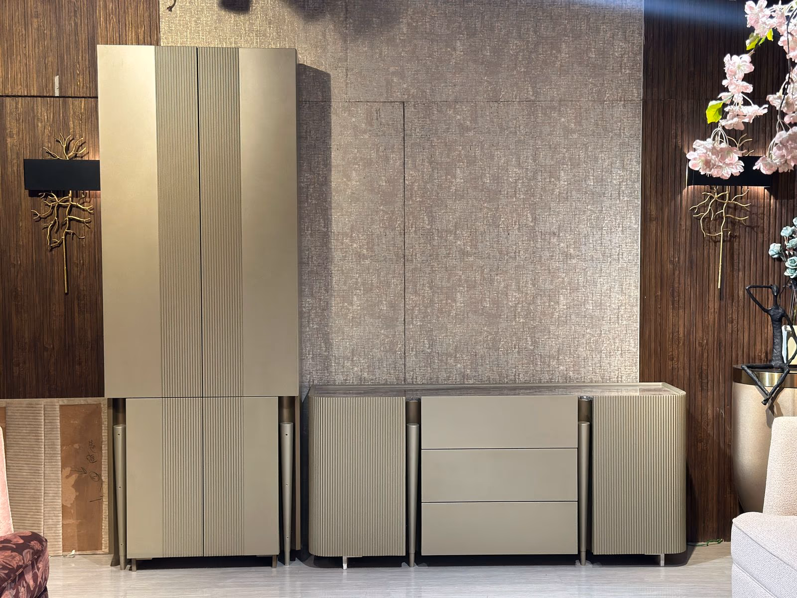 Champagne fluted tall cabinet paired with a matching three-drawer sideboard on tapered brass legs in a showroom.