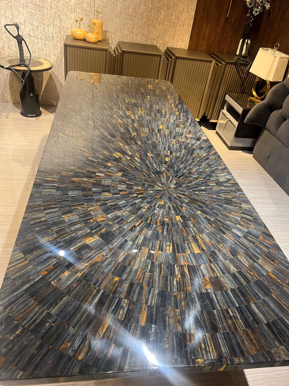 Dining table top cut and set in a radial sunburst pattern of blue-grey and gold semi-precious stone in a showroom.