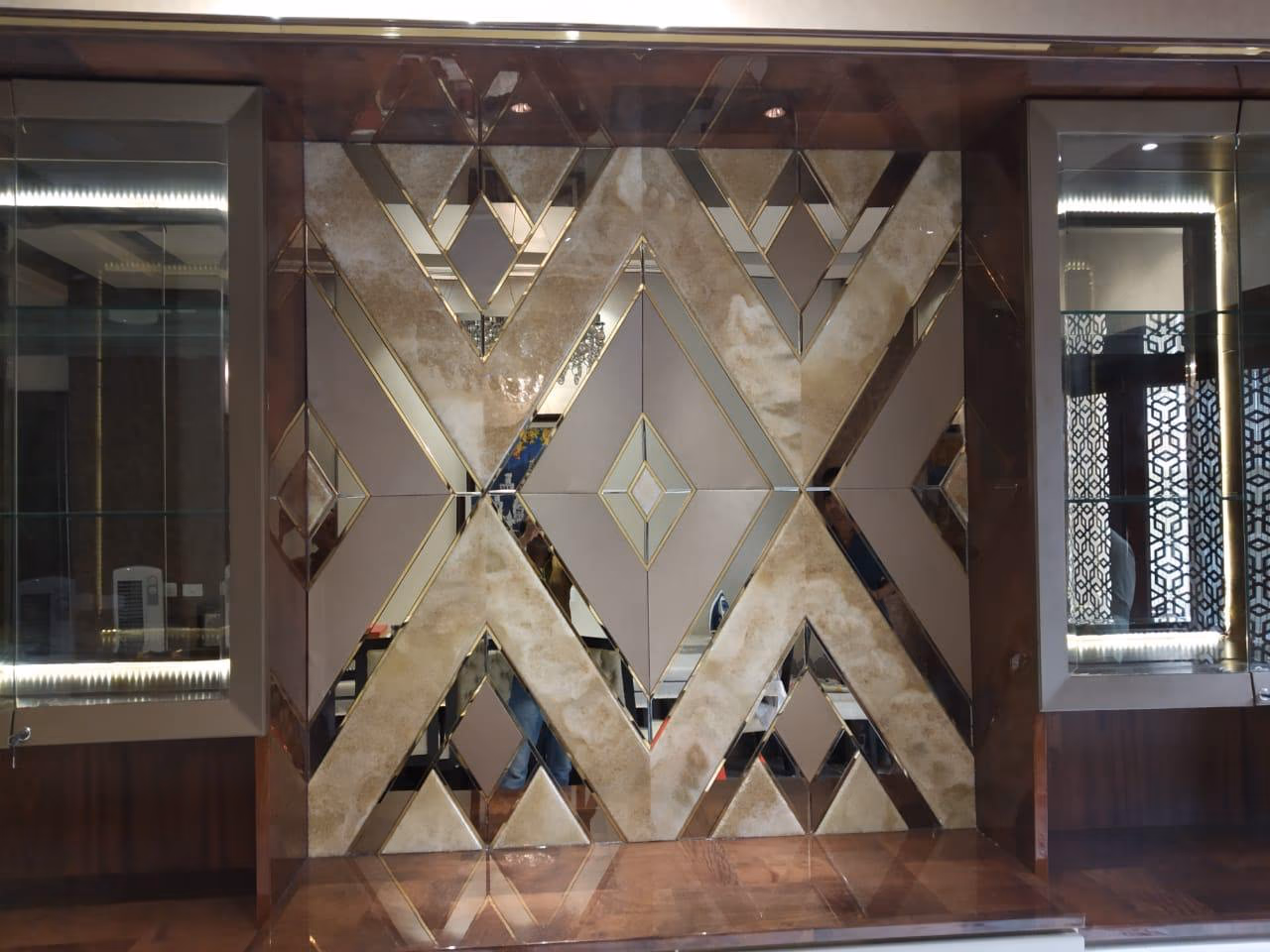 Detail of the display unit showing the two LED-lit glass side cabinets with glass shelves beside the bronze diamond mirror panel in a wood surround.