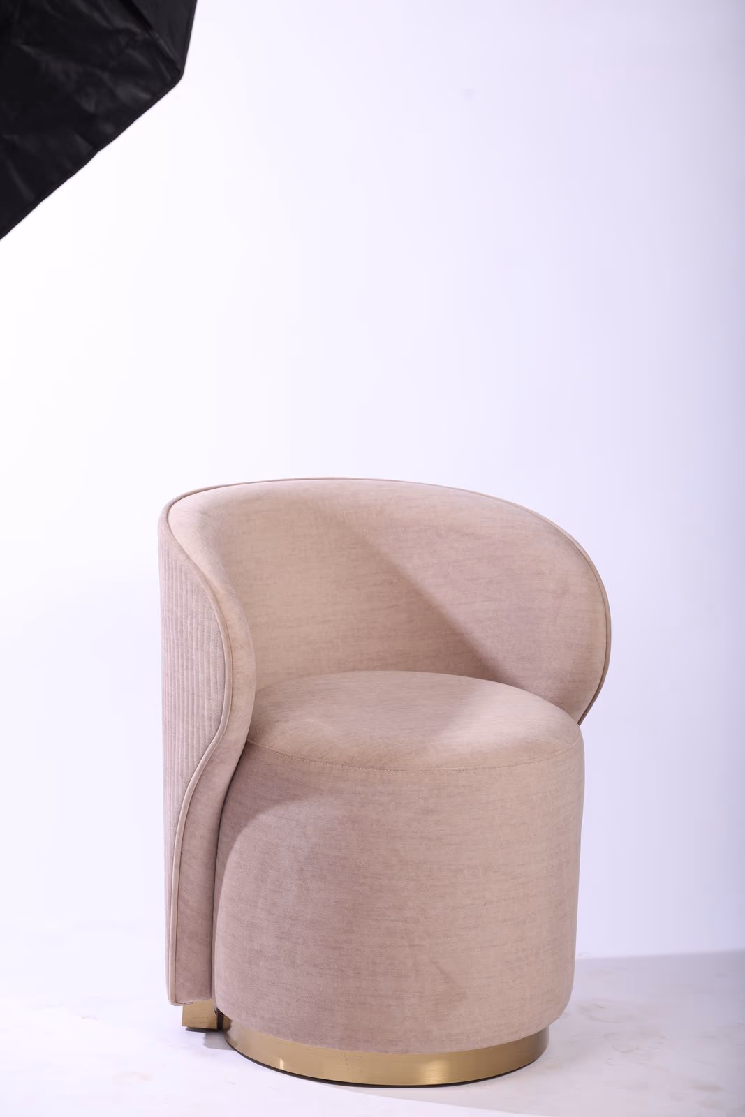 Beige upholstered barrel vanity chair with channel-tufted back and brushed brass swivel base.