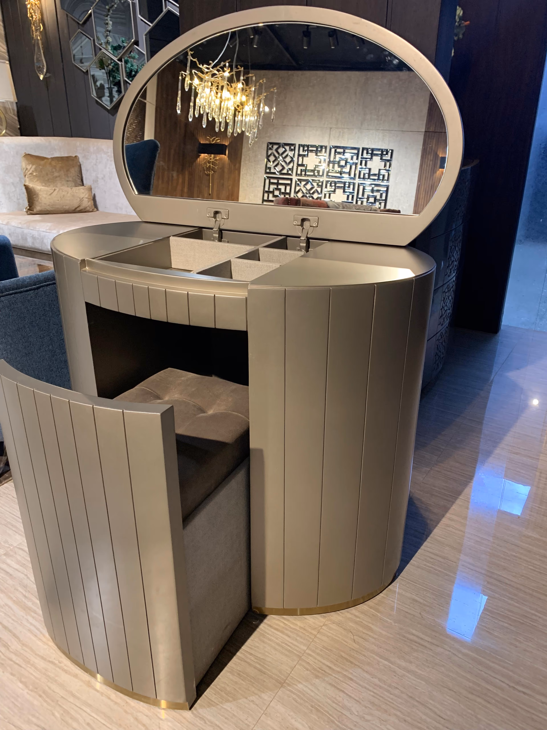 Round champagne dressing table with a lift-up oval mirror lid revealing lined jewellery compartments, a fluted body and a tucked-in upholstered stool.
