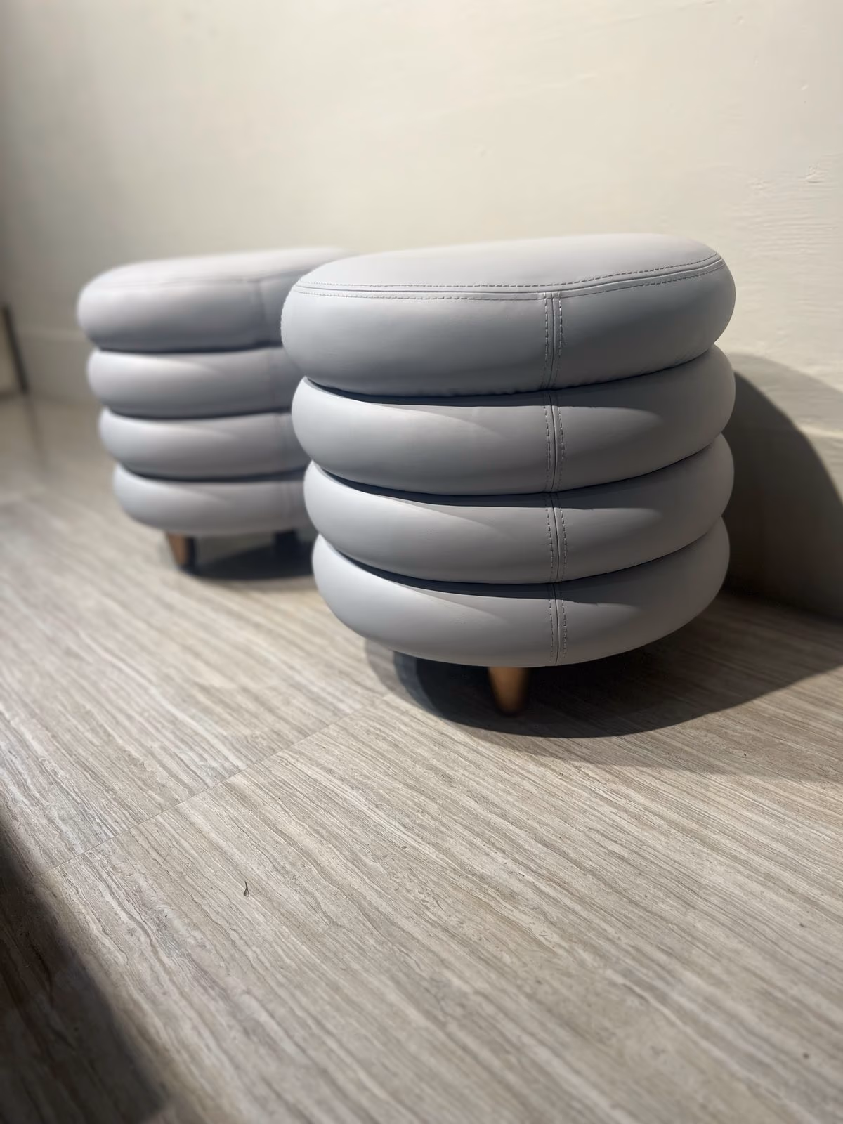 Pale grey leather vanity stool built from four stacked padded rings on short wood legs.
