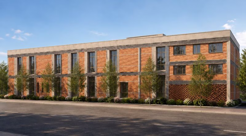 The front elevation of a purpose-built 80,000 sq ft furniture factory in warm brick and pale stone.