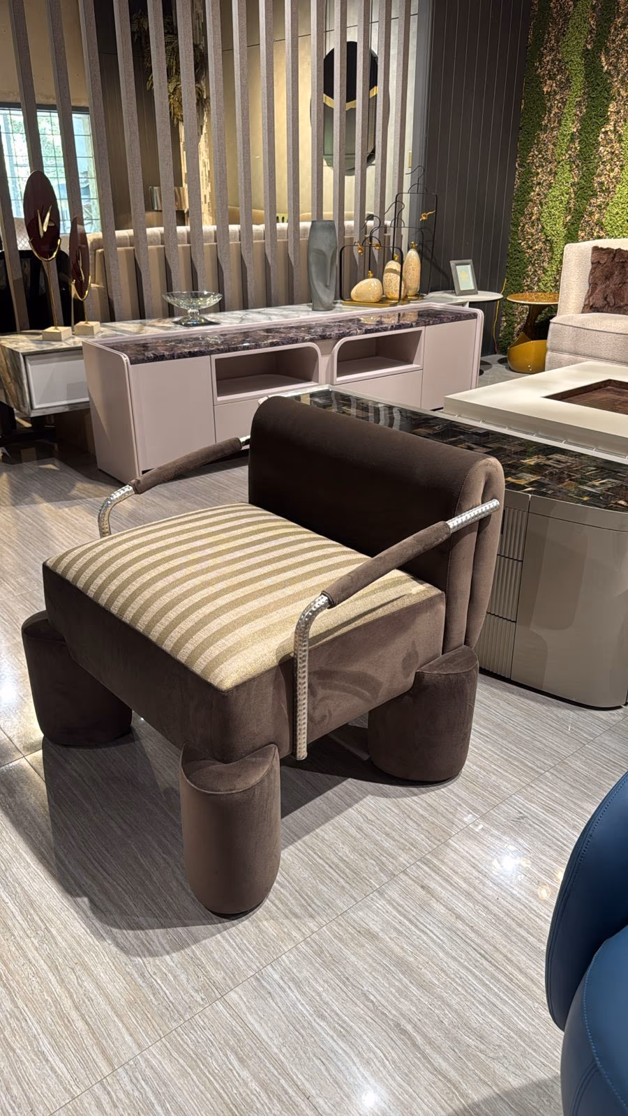 Brown velvet accent chair with a gold-and-cream striped seat and ribbed chrome armrests, made for an entrance.