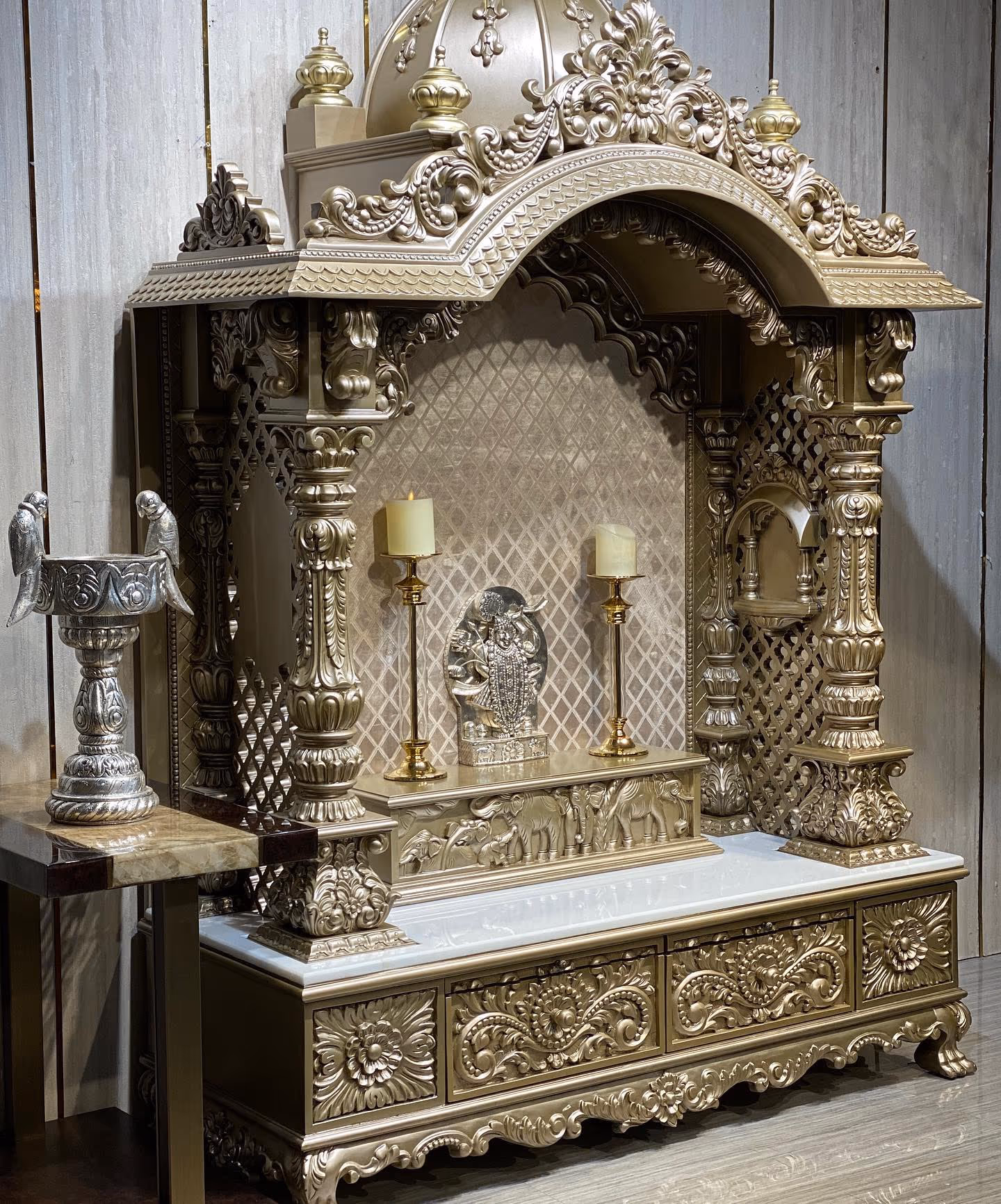 A custom wooden mandir (pooja unit) with warm lighting, built to fit the wall.