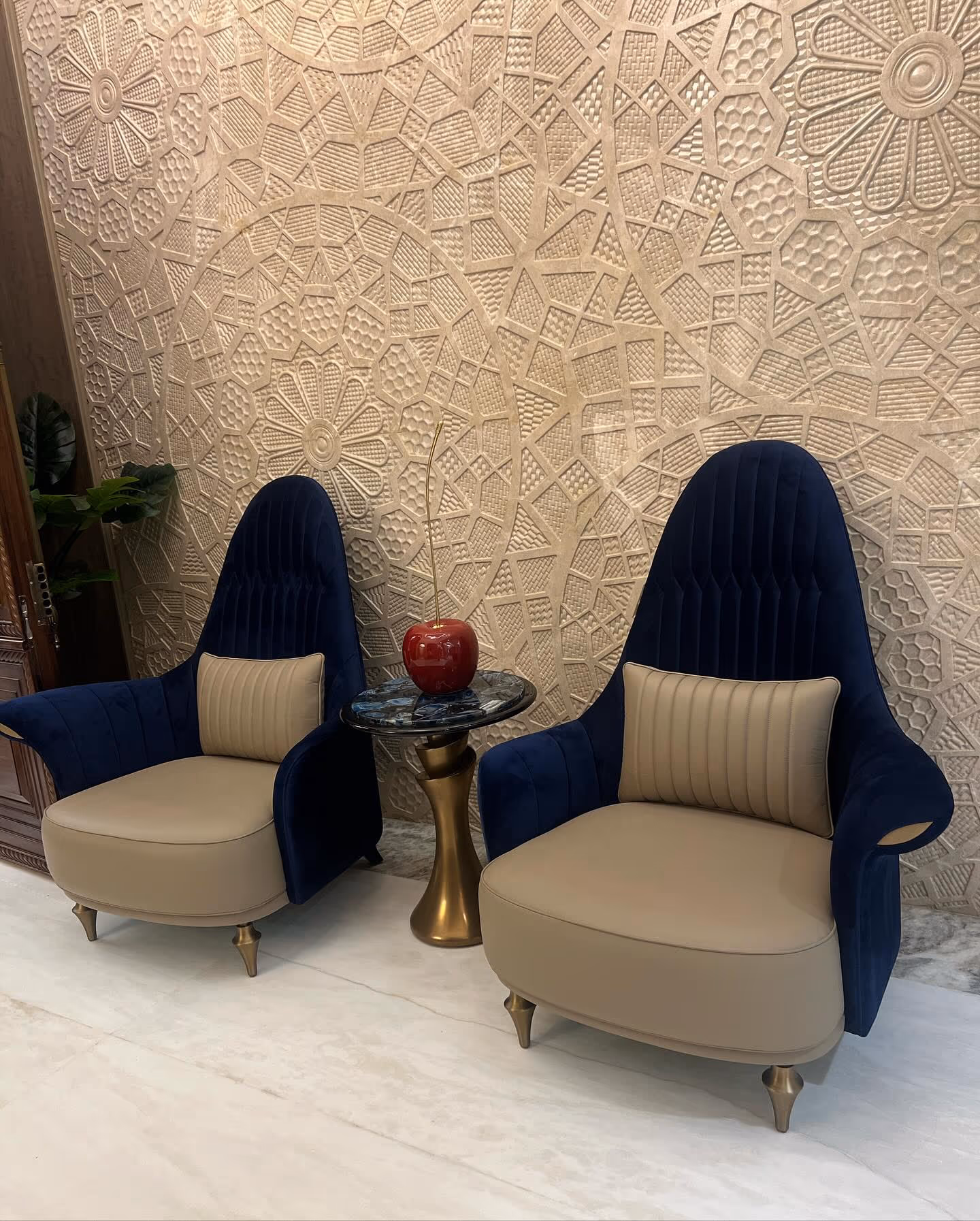 A Designatore living space — high-back velvet chairs against a carved relief wall.