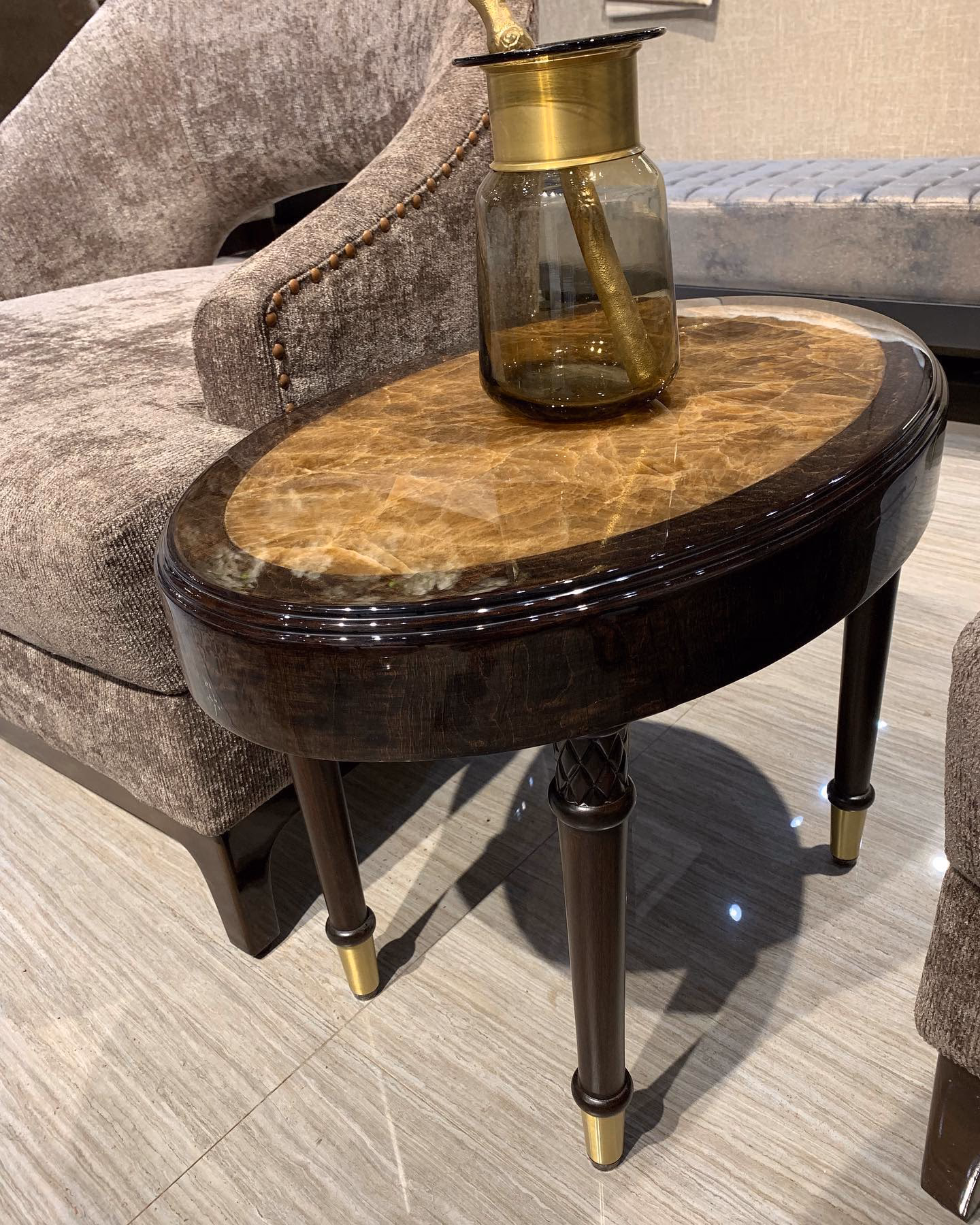 Oval side table with an amber onyx inset top, a high-gloss dark walnut rim, four turned tapered legs with a carved lattice detail and polished brass foot caps.