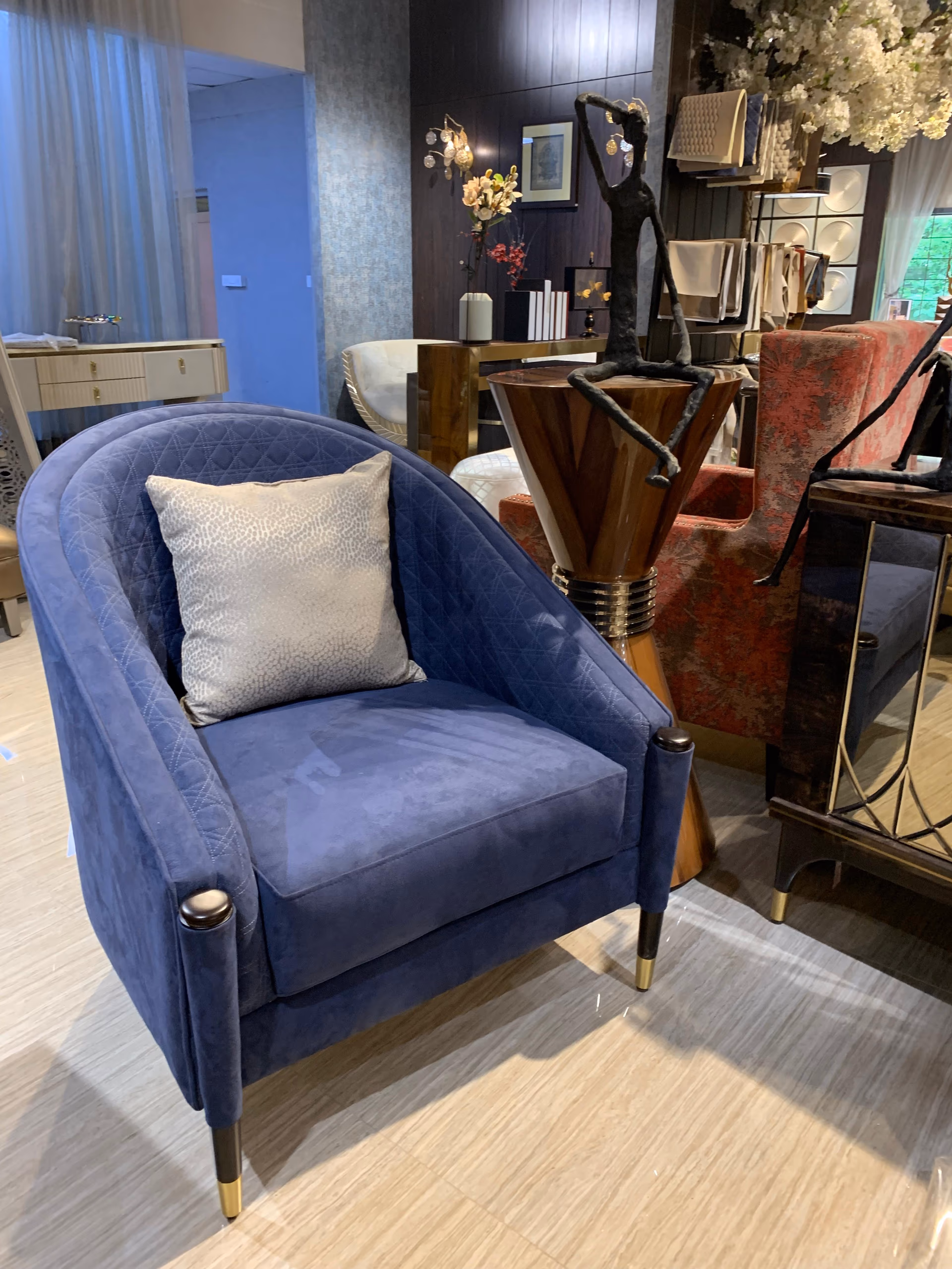 Deep blue velvet barrel accent chair with a rounded diamond-quilted back, loose seat cushion and dark tapered legs with brass caps.
