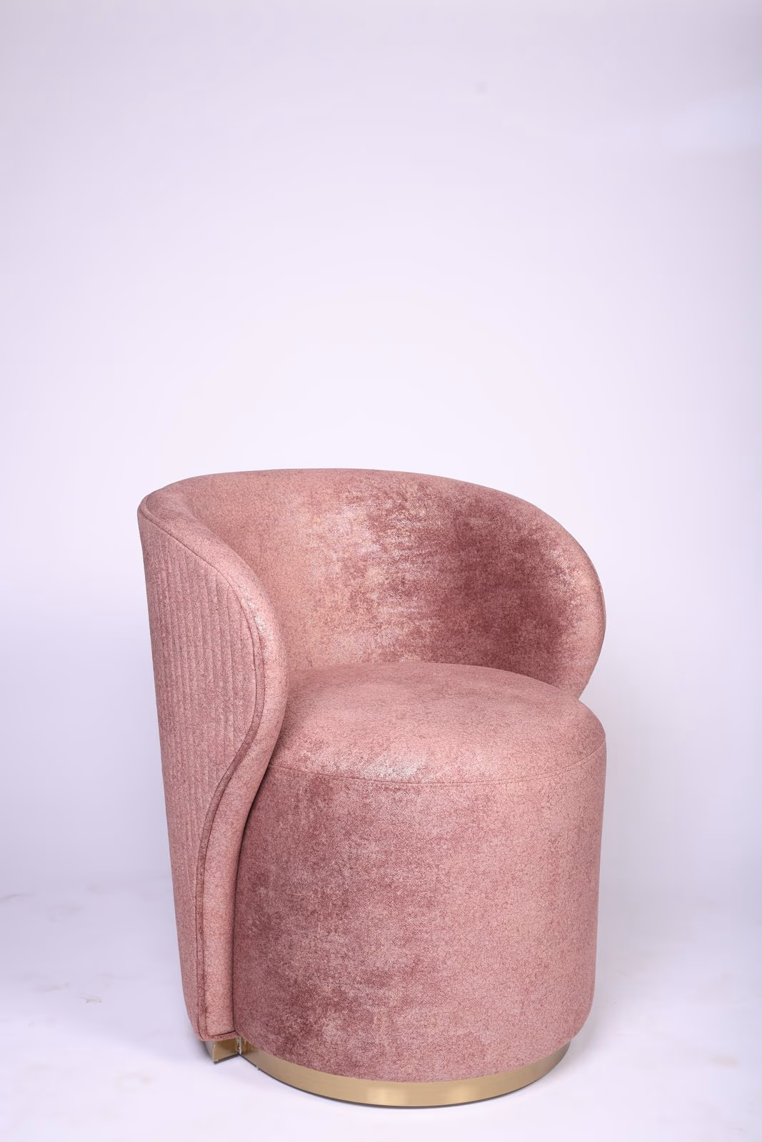 Dusty pink chenille barrel chair with a channel-tufted side panel and a brass ring base on a plain studio backdrop.