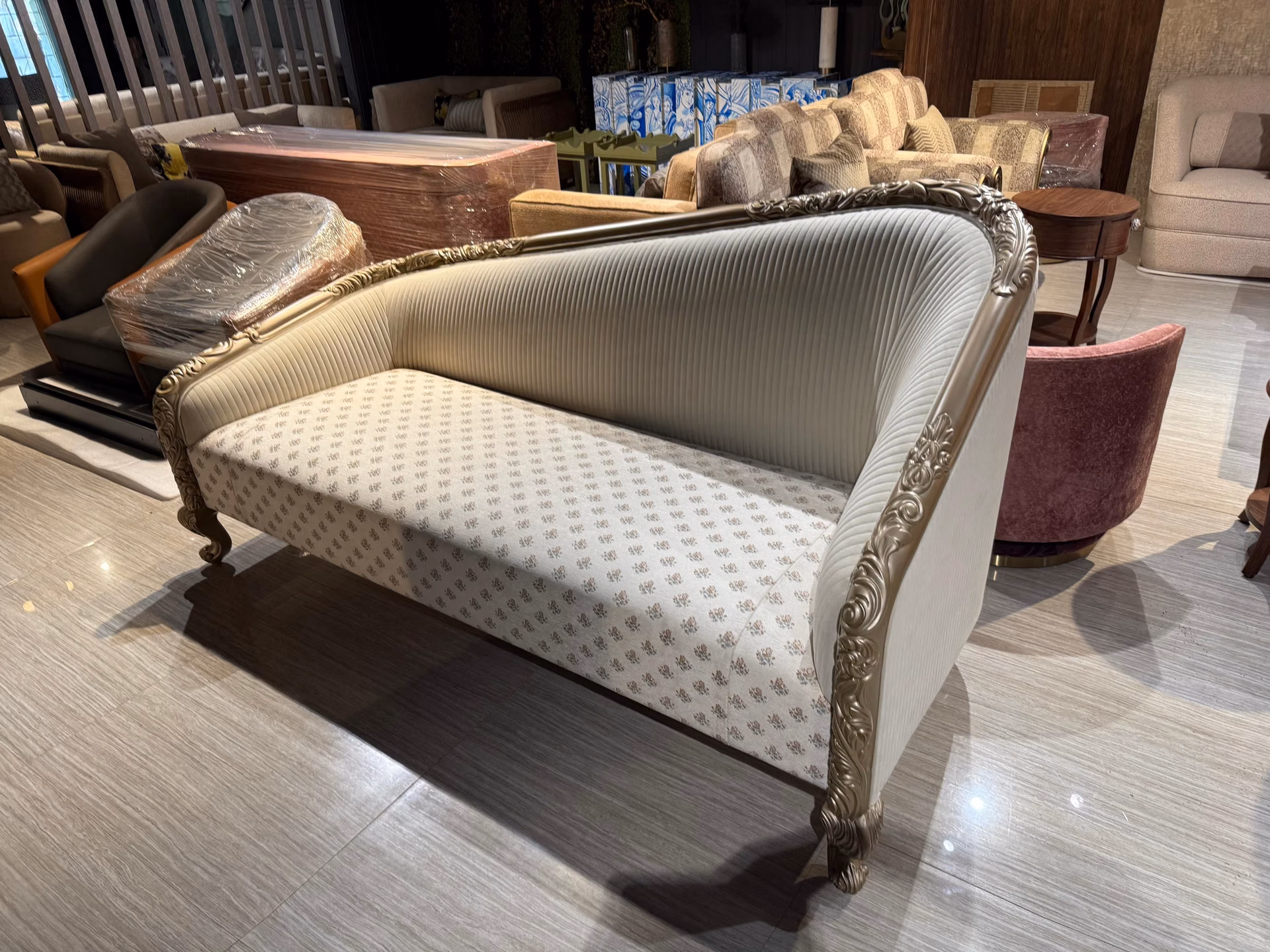 Two-seat sofa with a pleated cream back cushion, floral patterned seat and a hand-carved champagne gold wood frame.