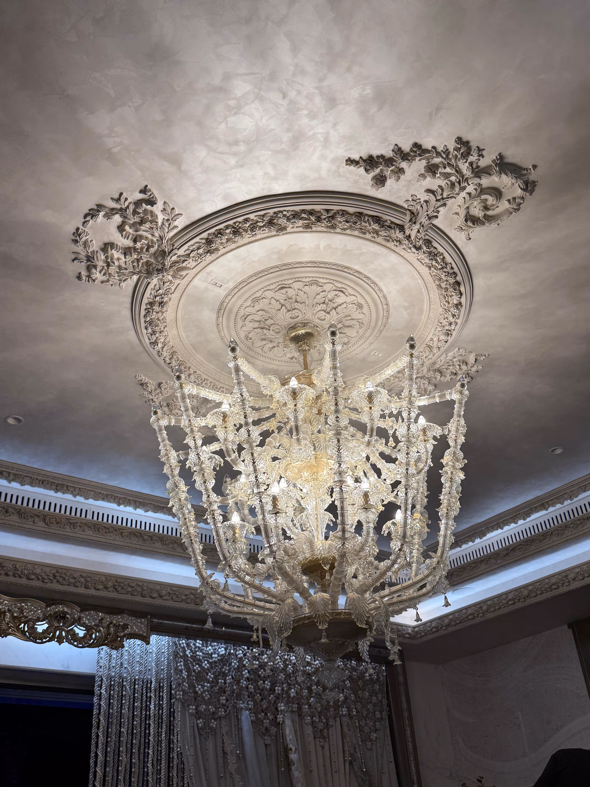 Multi-tier crystal chandelier with cascading glass beads hanging from a carved floral ceiling medallion.