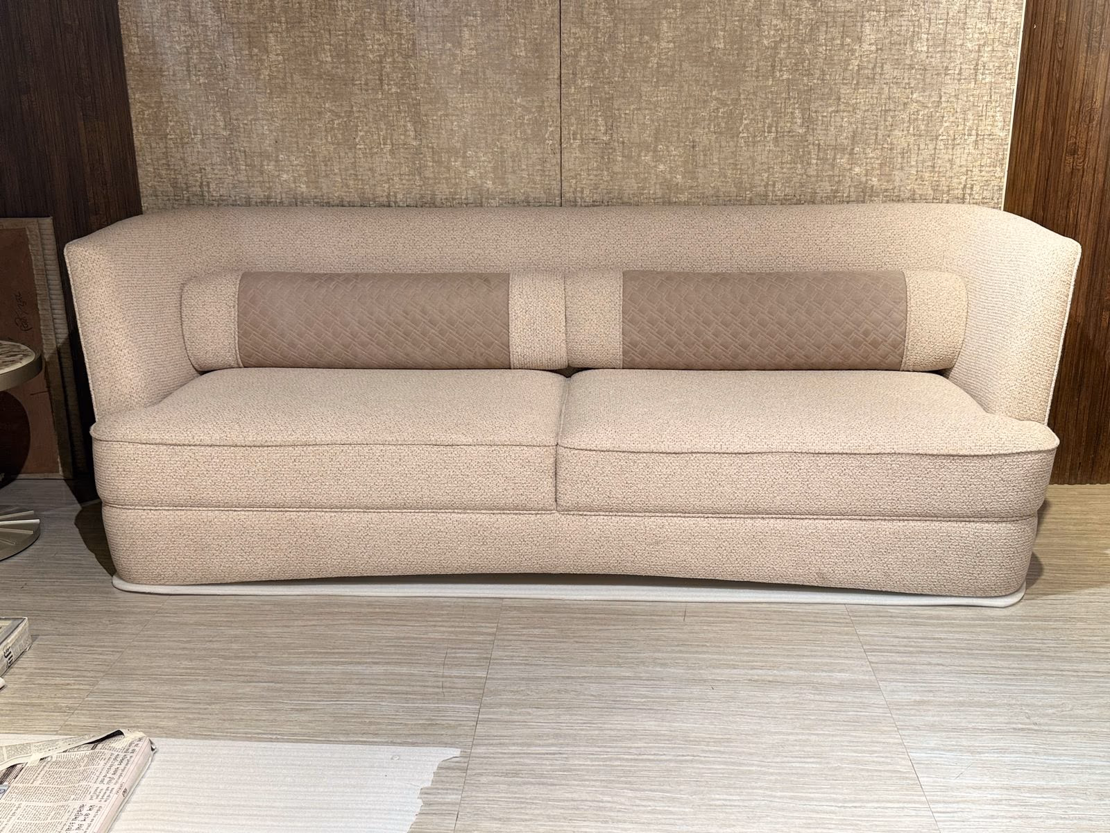 Cream boucle sofa with a long lattice-quilted bolster running the width of the backrest against a textured wall panel.