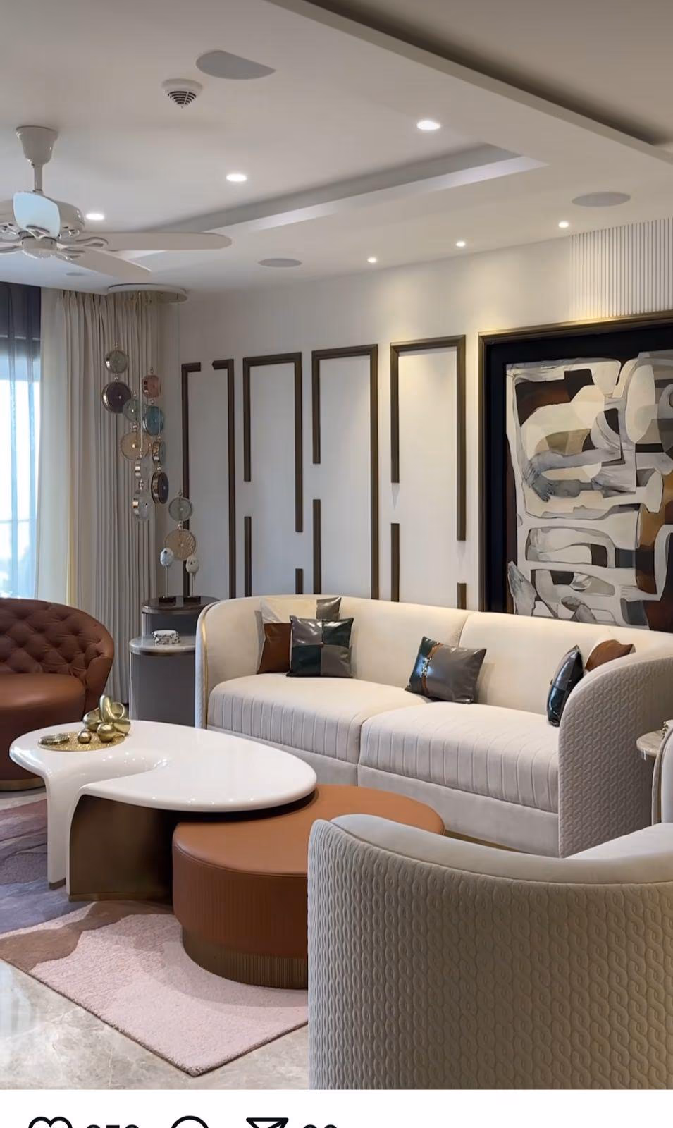 Living room with a curved channel-cushion sofa, cognac leather tufted chair, sculptural white coffee table and terracotta ottoman.