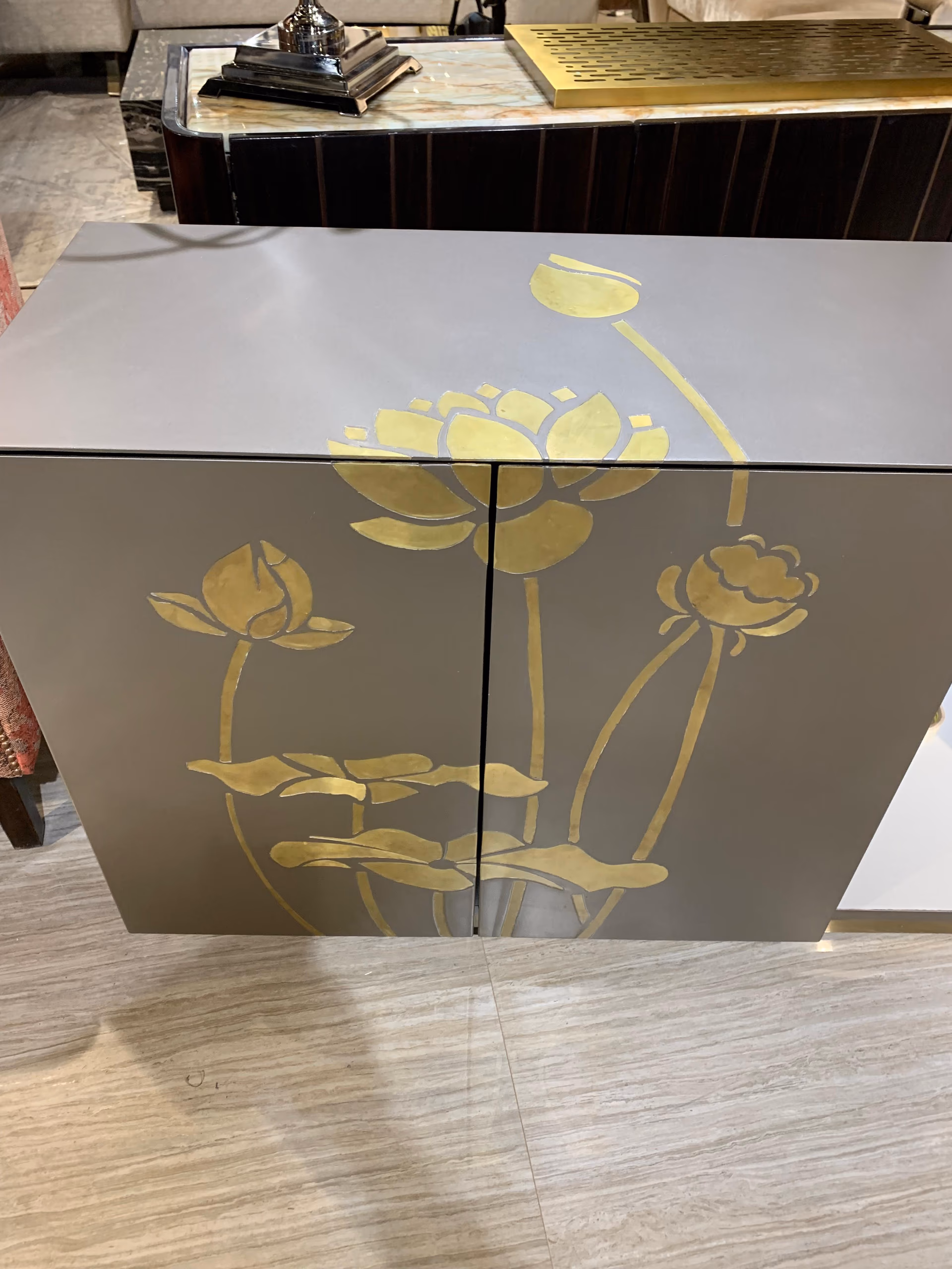 Higher angle of the lotus cabinet showing the gold design continuing over the top surface and the clean grey edges.
