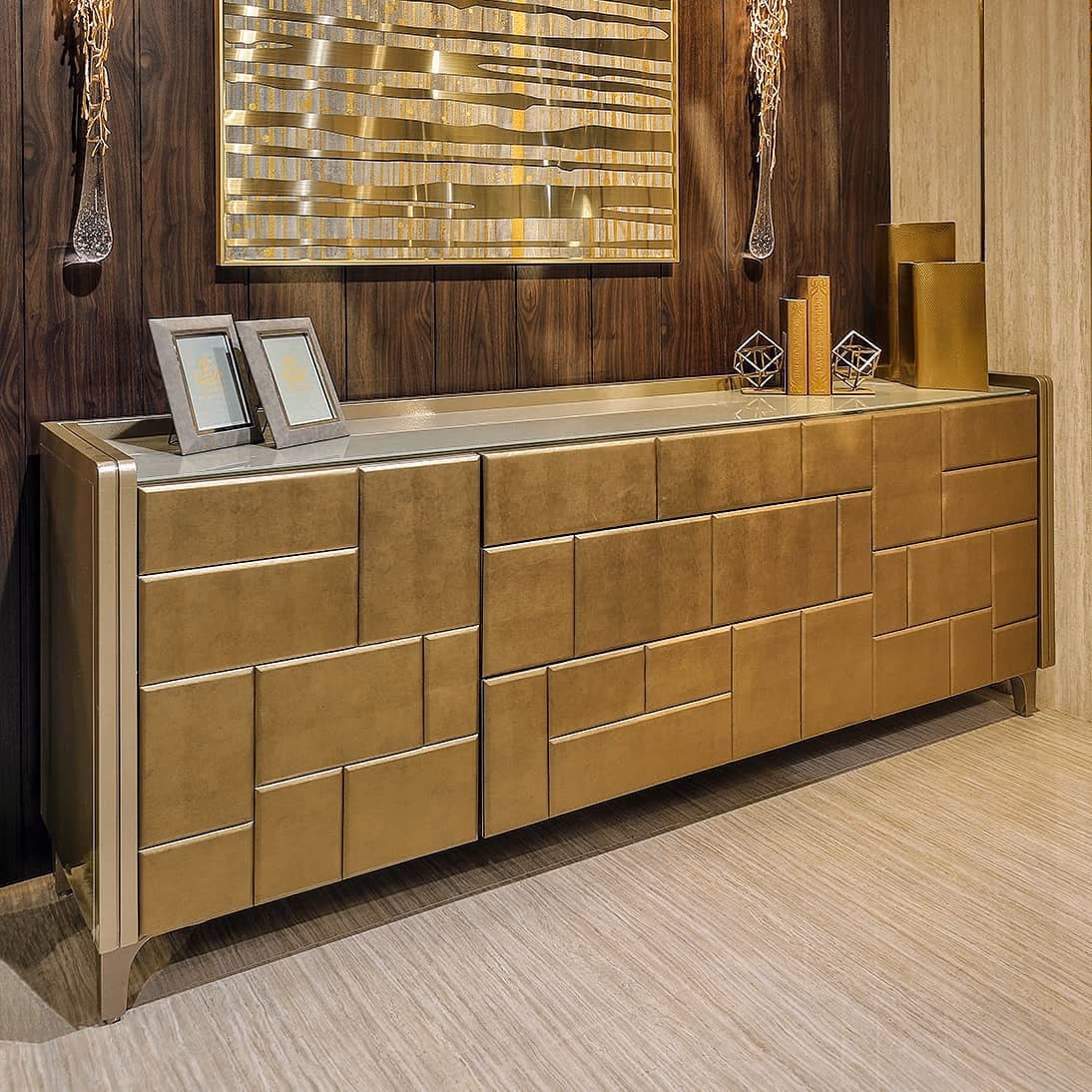 Long sideboard clad in antique-gold suede panels laid in a staggered brick pattern, framed in champagne metal with a mirrored top and sculpted corner legs.
