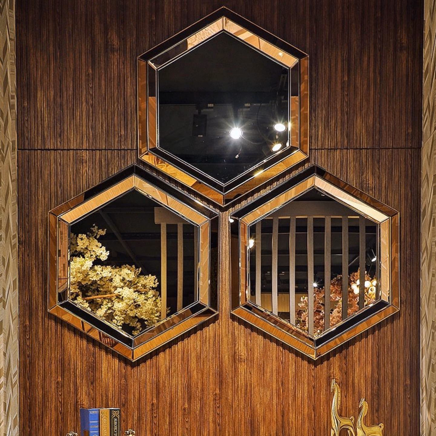 Close view of the three hexagonal bevelled mirrors on walnut panelling, showing the bronze-tinted mitred frames and the depth of each hand-cut bevel.