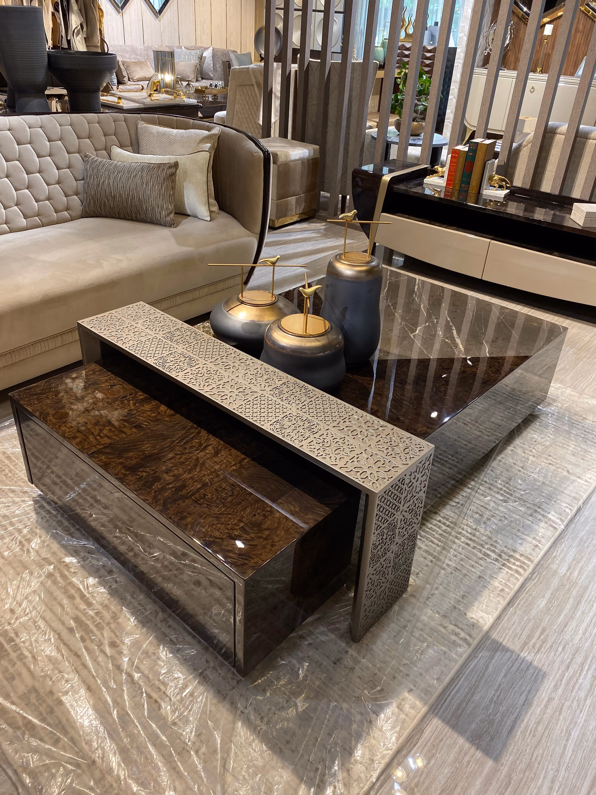 Angled view of the marble cube table with the silver filigree nesting table pulled out and a curved beige sofa behind.
