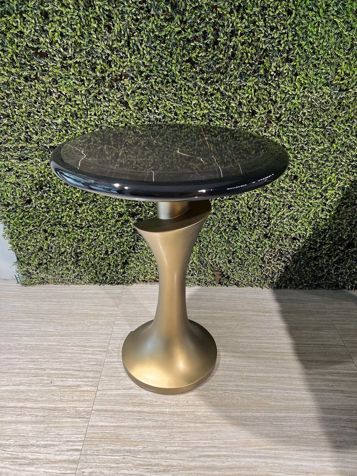 Round black marble-top side table balanced on a sculpted matte gold tulip-shaped pedestal base.