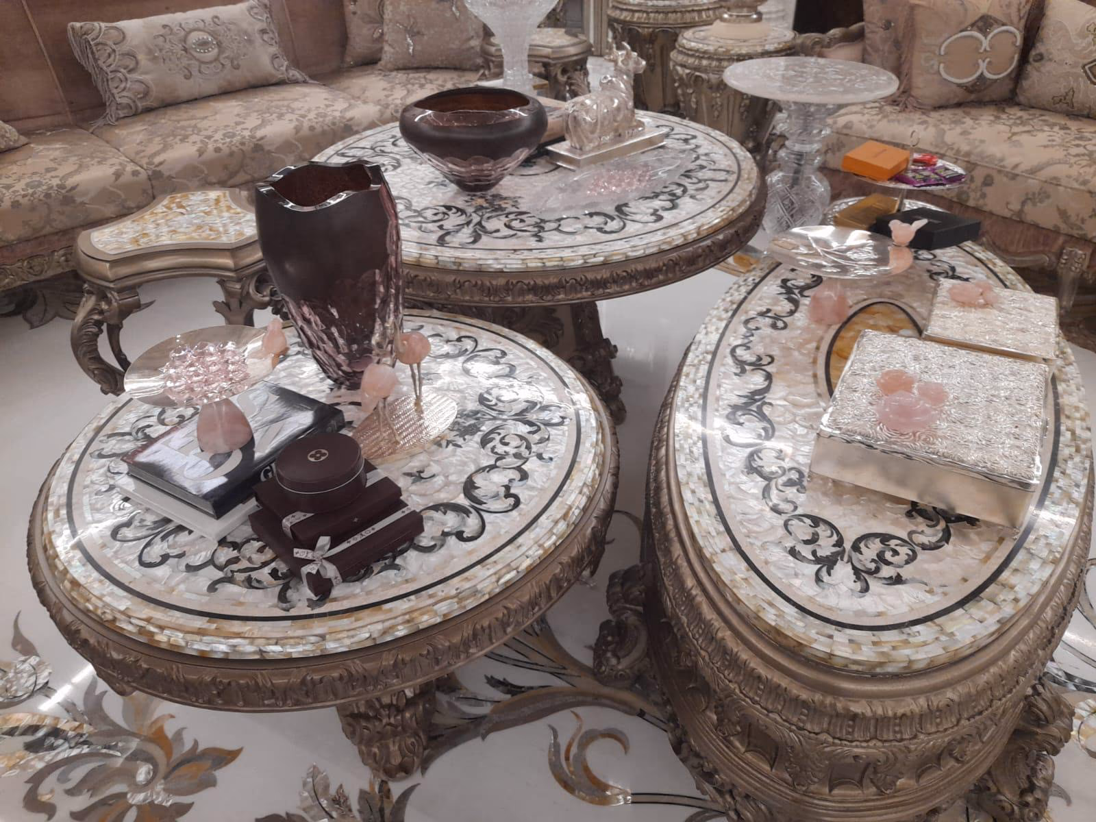 Mother-of-pearl inlay nesting coffee tables with carved silvered bases in a living room