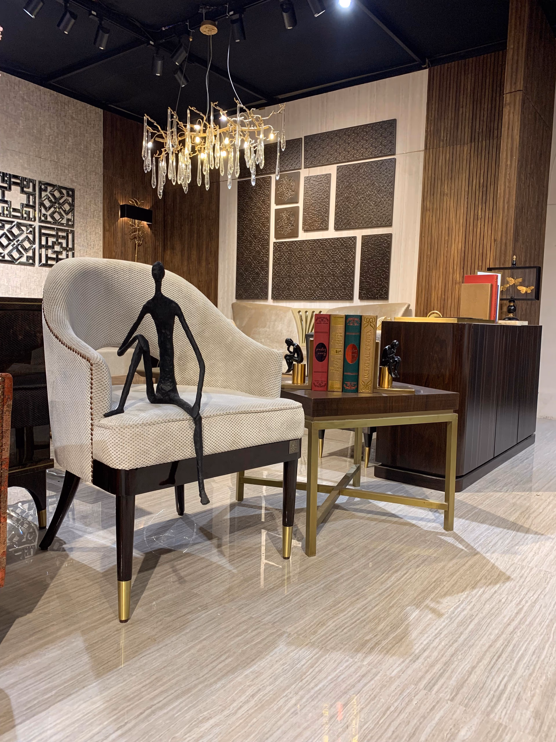 Curved-back barrel accent chair in oatmeal dotted woven fabric on dark wood legs with brass caps, next to a walnut and brass square side table.