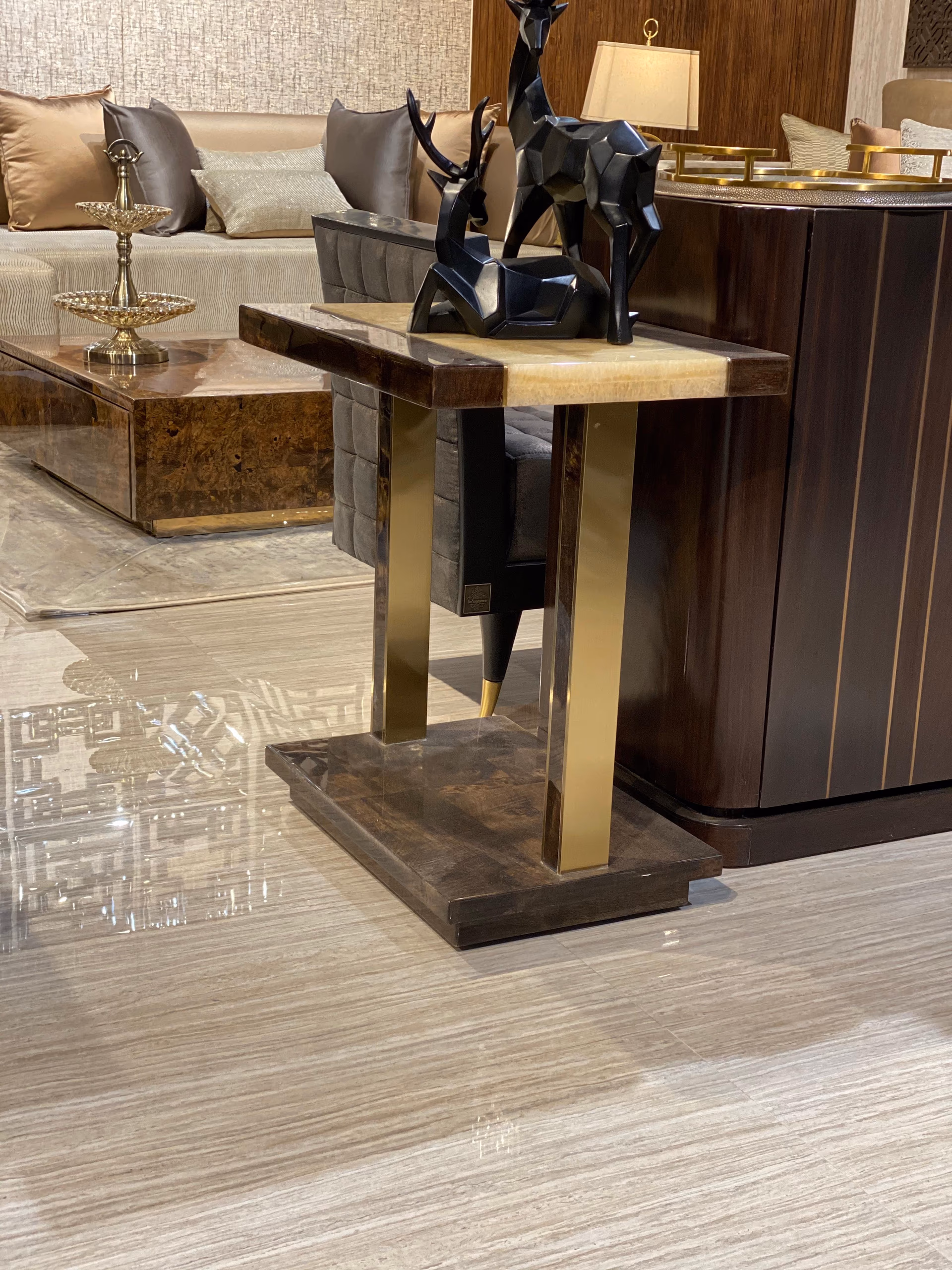 C-shaped side table with a cream onyx top and a warm burl-wood and brass frame, designed to slide over a sofa arm or under a seat.