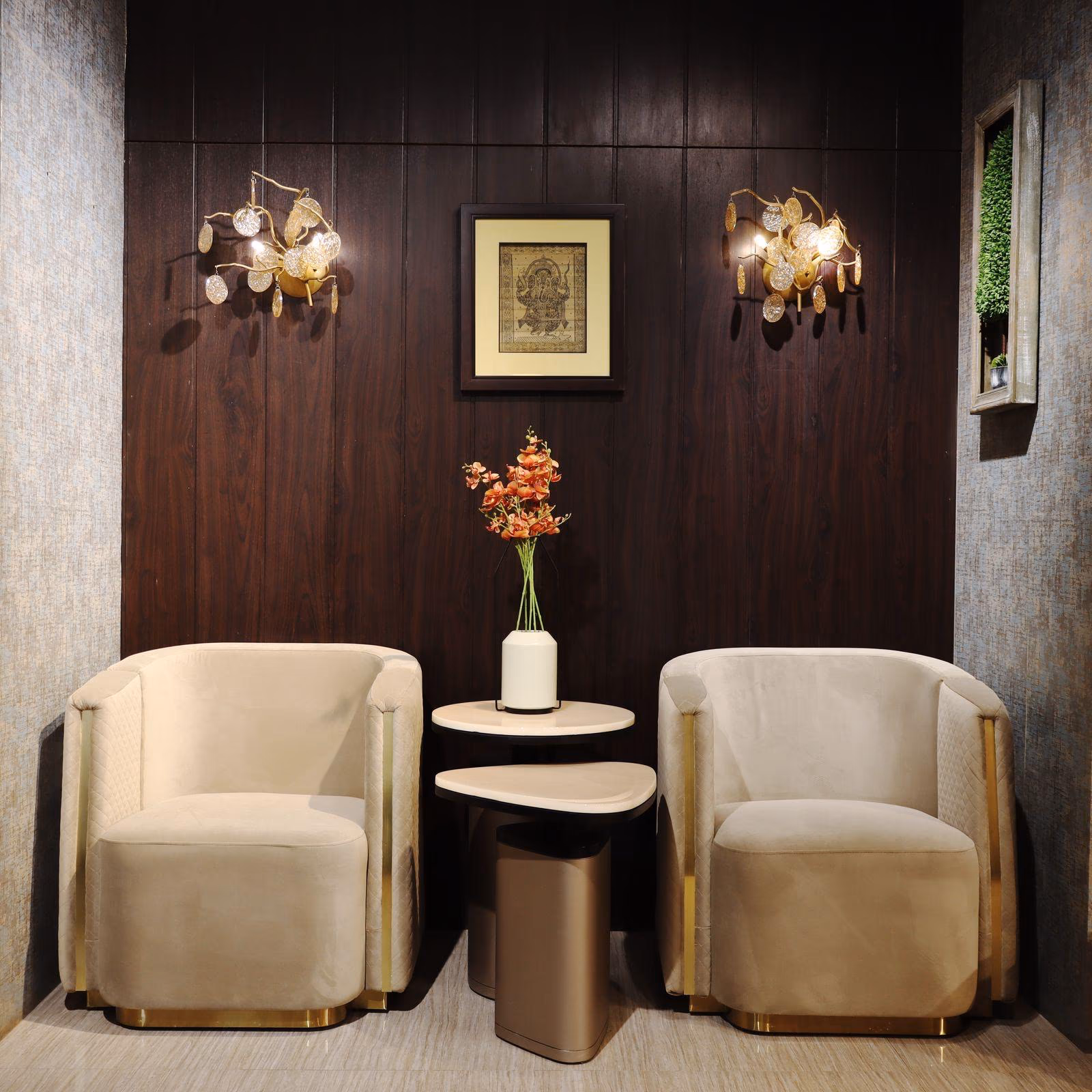 Pair of cream velvet barrel chairs with diamond-quilted sides and brass-edged legs beside a two-tier stone side table.