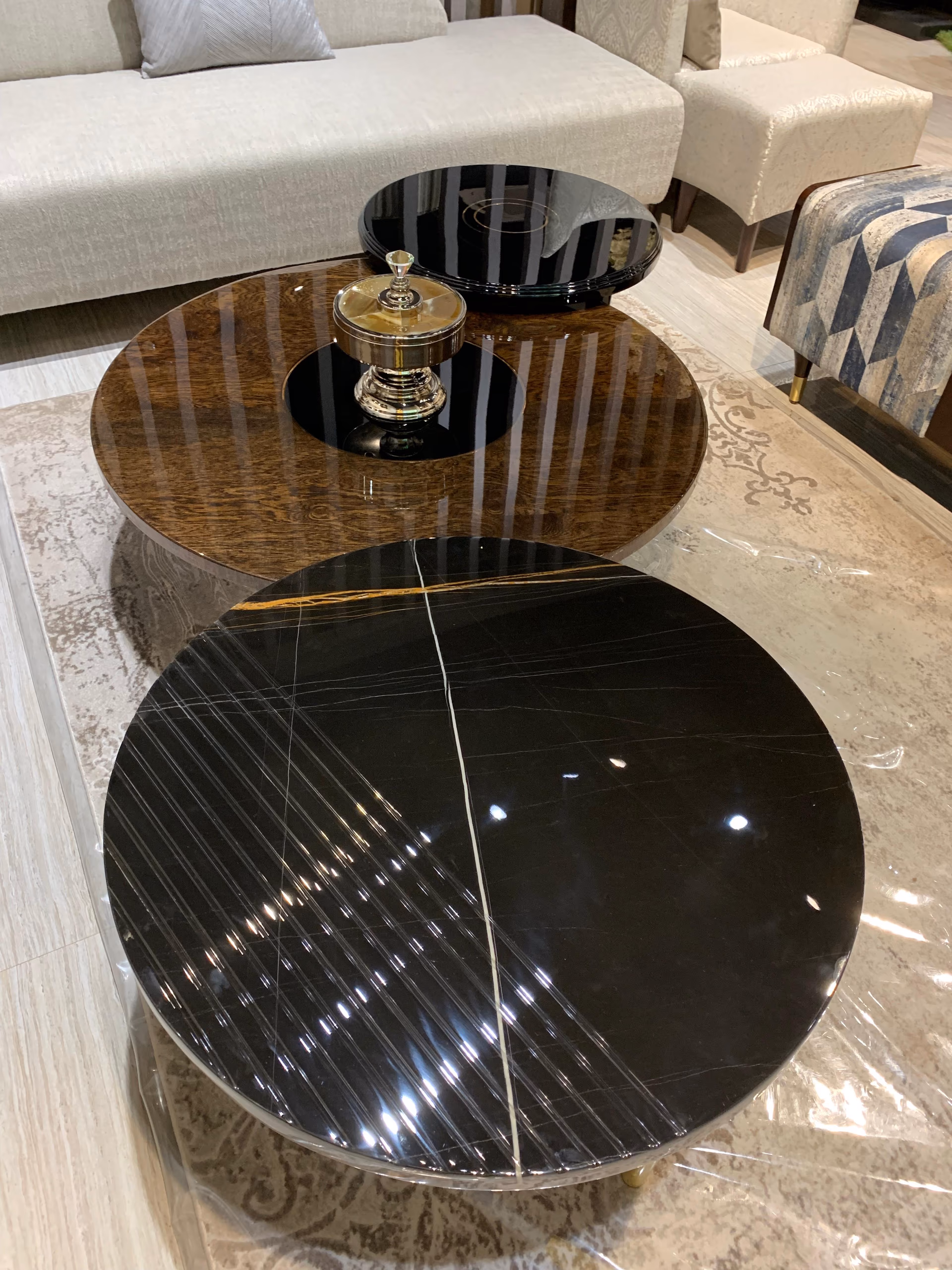 Overhead view of the three round coffee tables showing the black lacquer disc, the swirling burl-wood grain and the veined black marble top side by side.