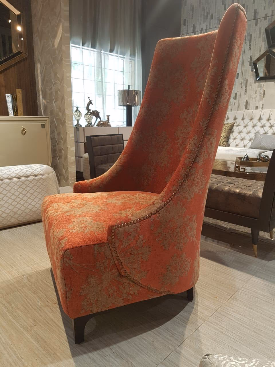 Back and side view of the rust floral wing chair, showing the tall curved back, a studded seam down the wing and dark wood feet.