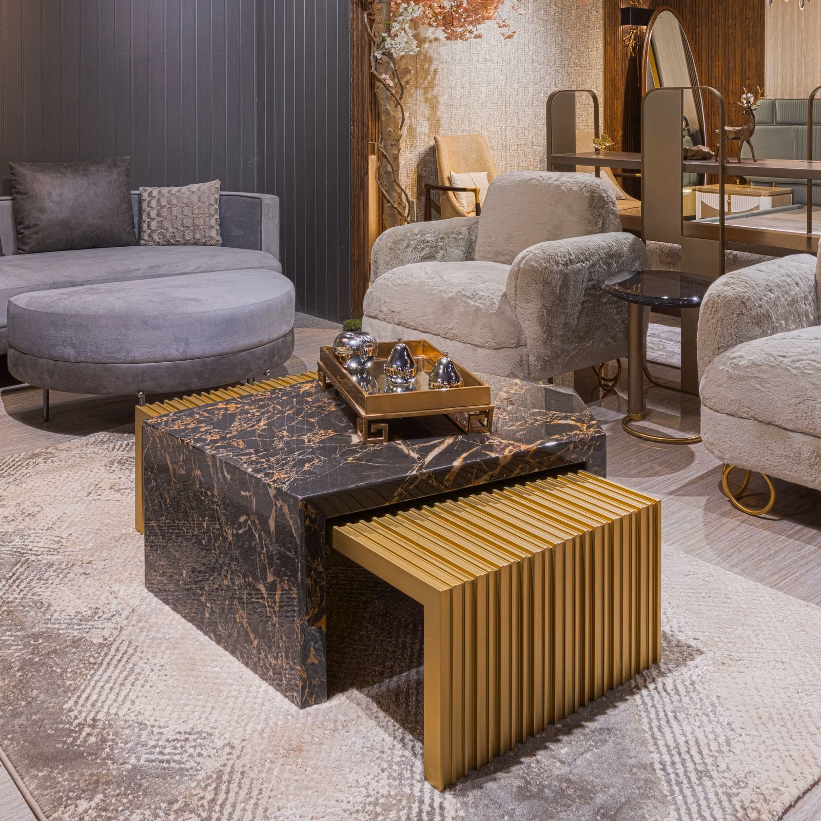 Living room corner with a rust-veined marble and fluted brass nesting coffee table set among grey and cream shearling seating.