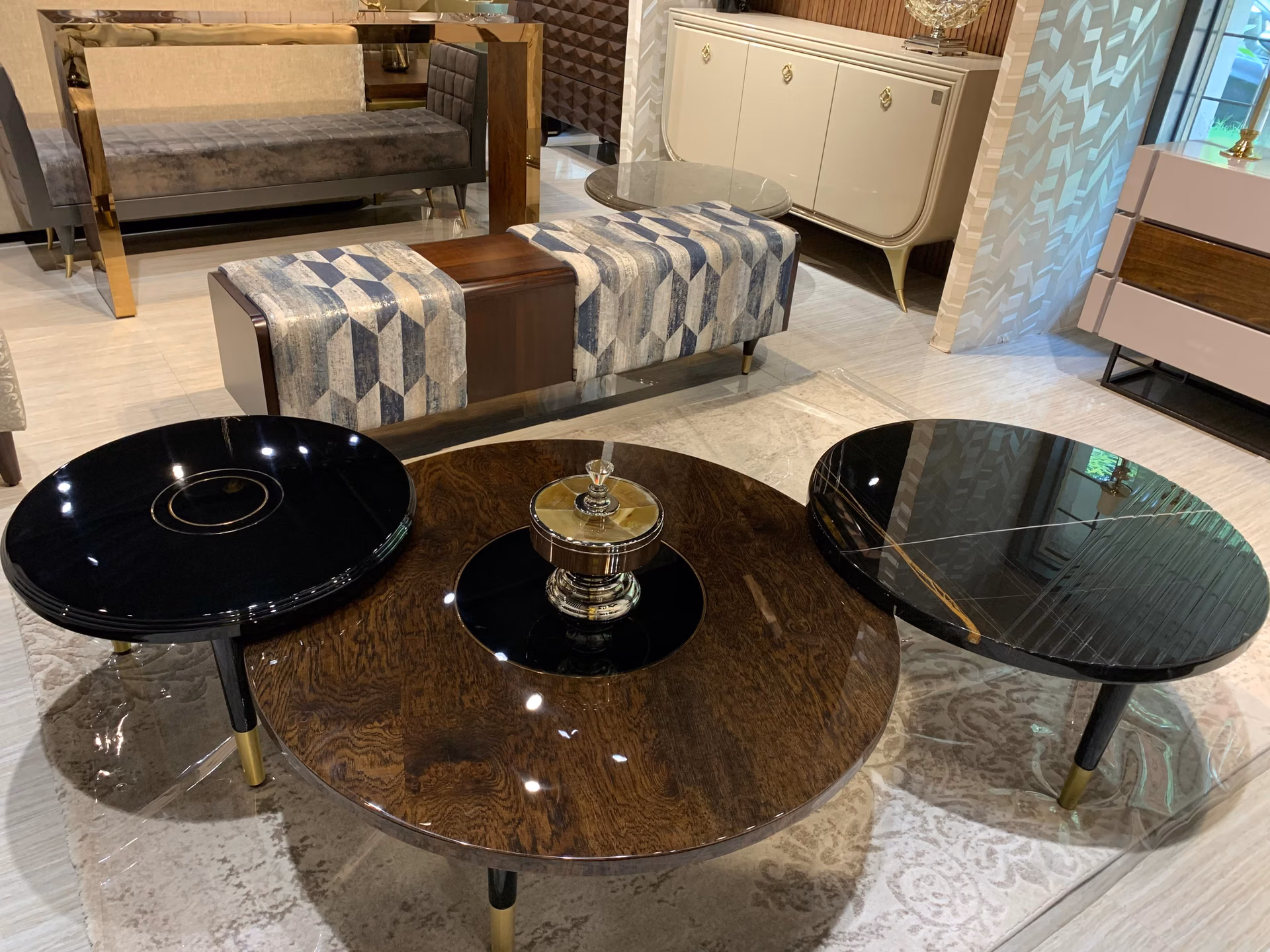 Set of three round coffee tables at different heights with black lacquer, dark burl-wood and black marble tops, each on splayed black legs with brass caps.