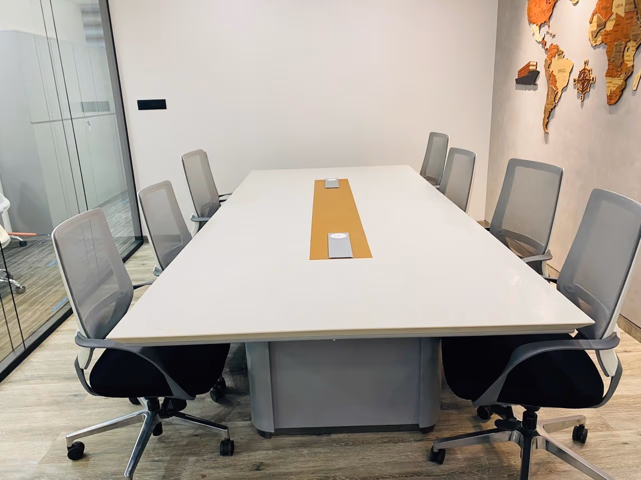 Boardroom with a white quartz conference table and wooden world map wall.