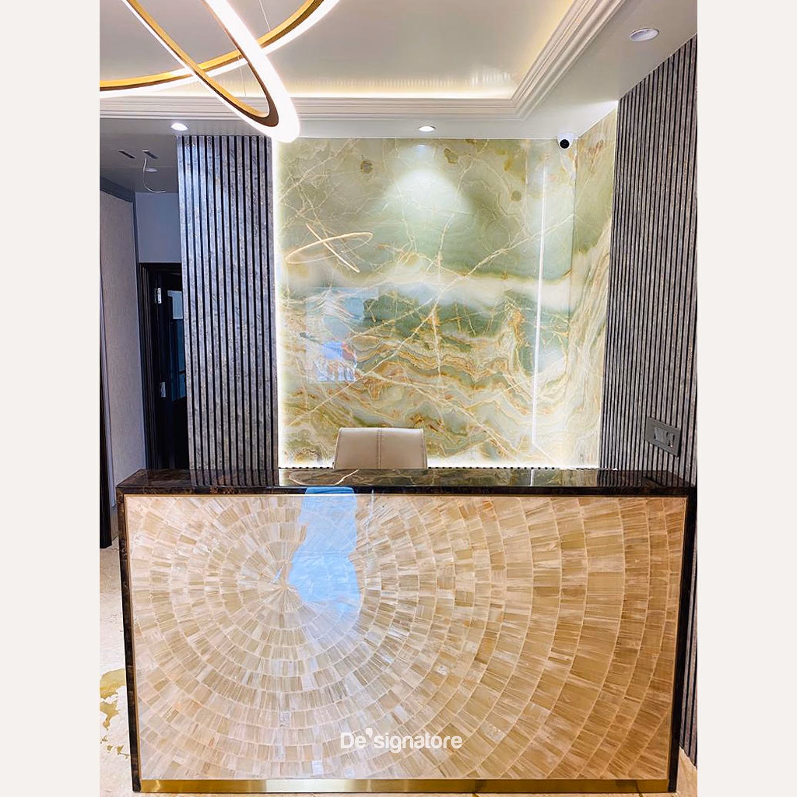 A backlit onyx reception desk with a brass-trimmed front and a stone top.