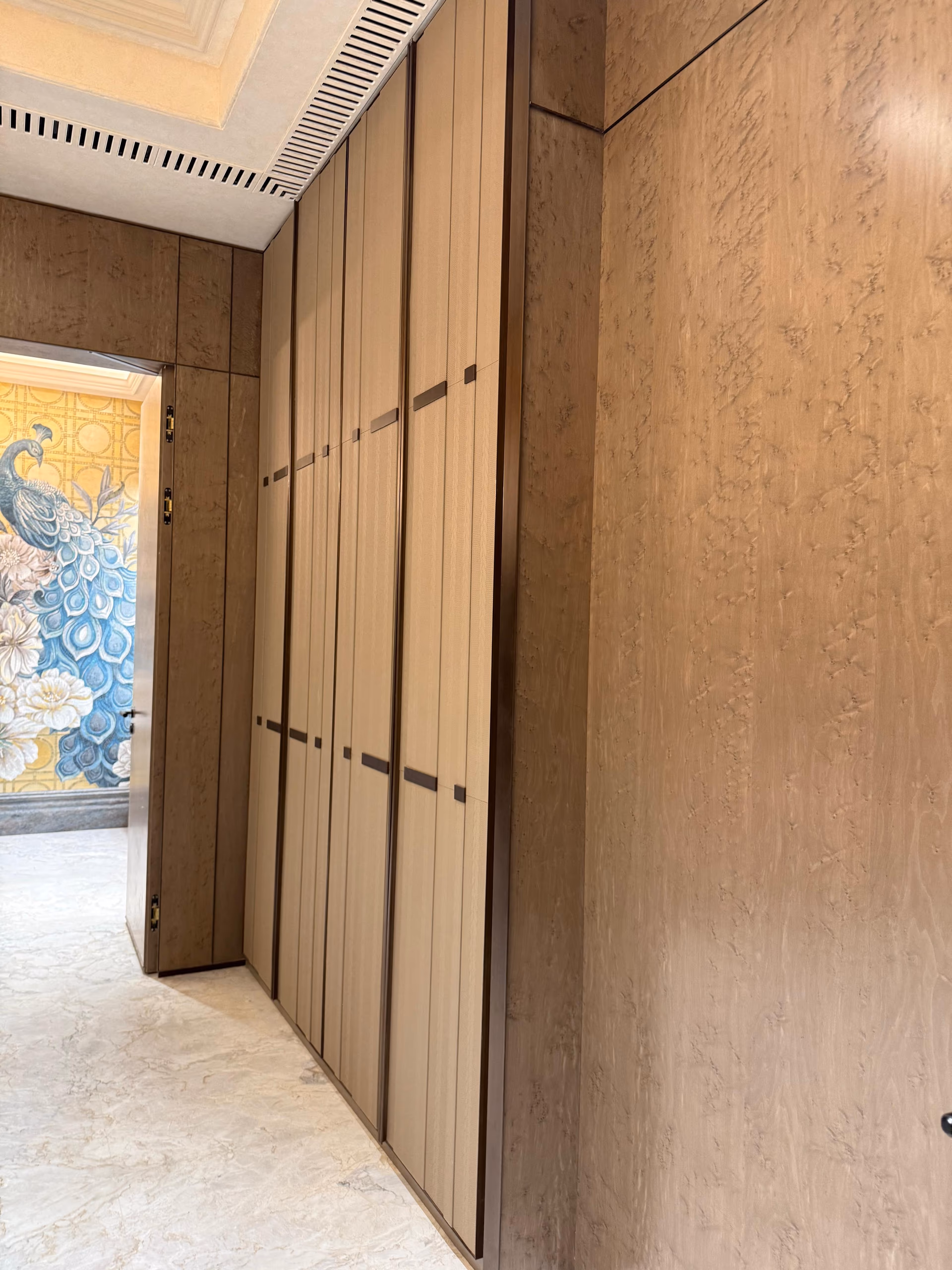 Natural wood veneer panels with flowing matched grain on a luxury wardrobe front.