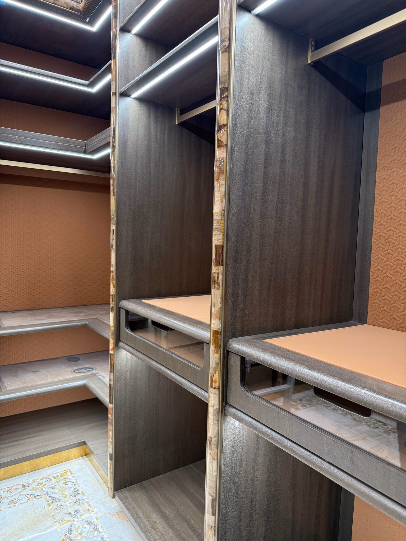 The corner of a made-to-measure walk-in wardrobe, showing hanging rails, open shelves and drawers built to the wall.
